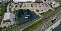 Aerial view of a vacant lot labeled “1 Acre Lot” beside a road and parking area