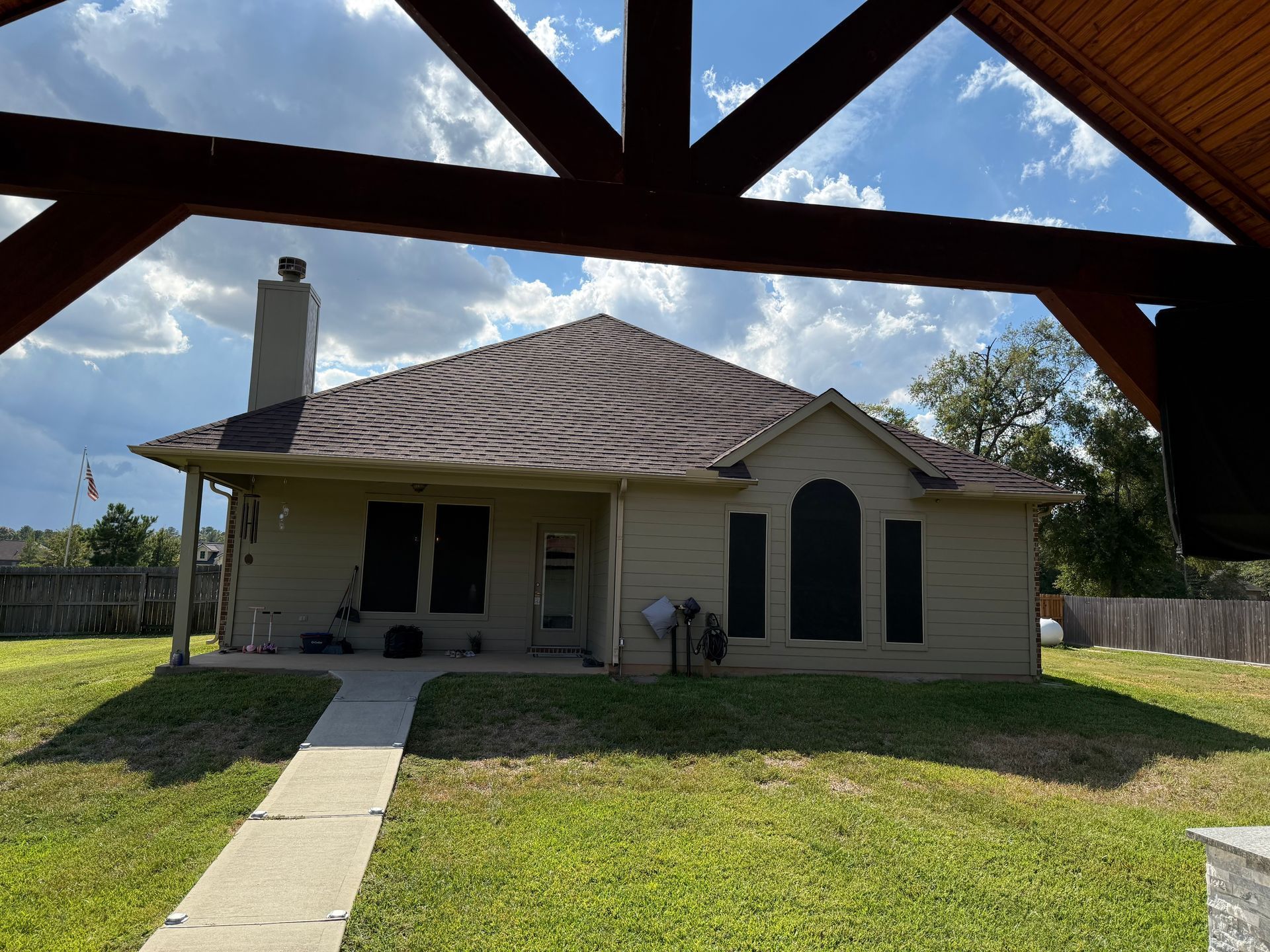 Single-story beige house with a tiled roof, front porch, and a walkway across a green lawn.