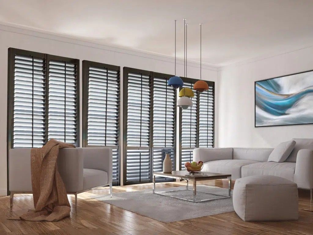 A living room with a couch , chairs , coffee table and shutters.