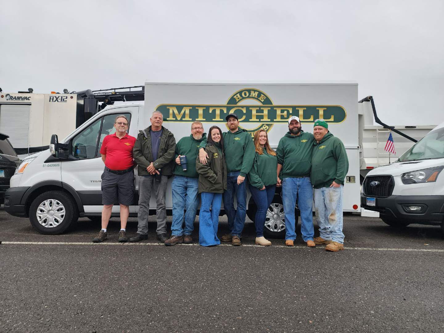 A group of people are posing for a picture in front of a mitchell truck.
