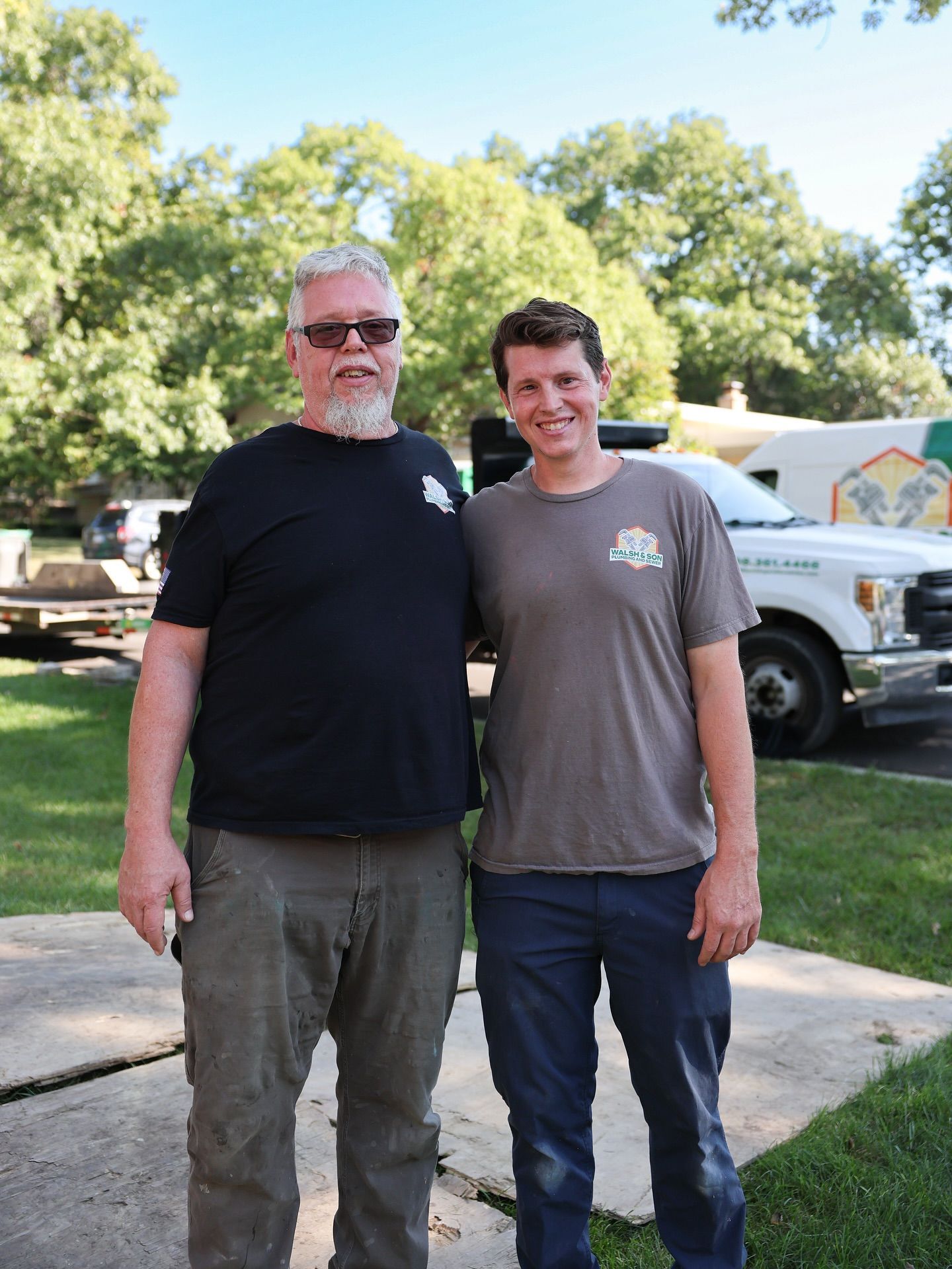 Man in orange shirt working on plumbing in wooden wall frame.
