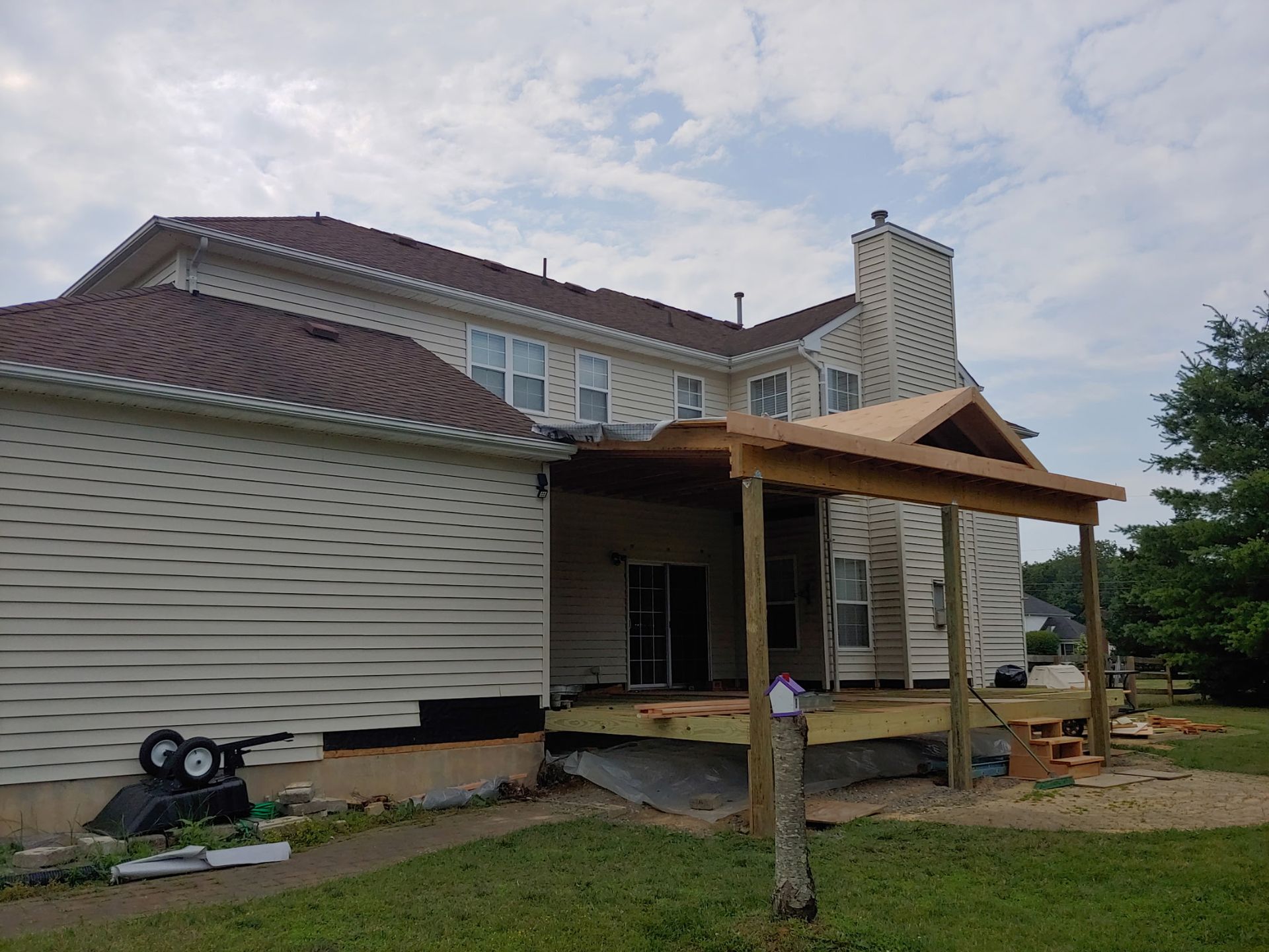 A large white house with a wooden deck under construction.
