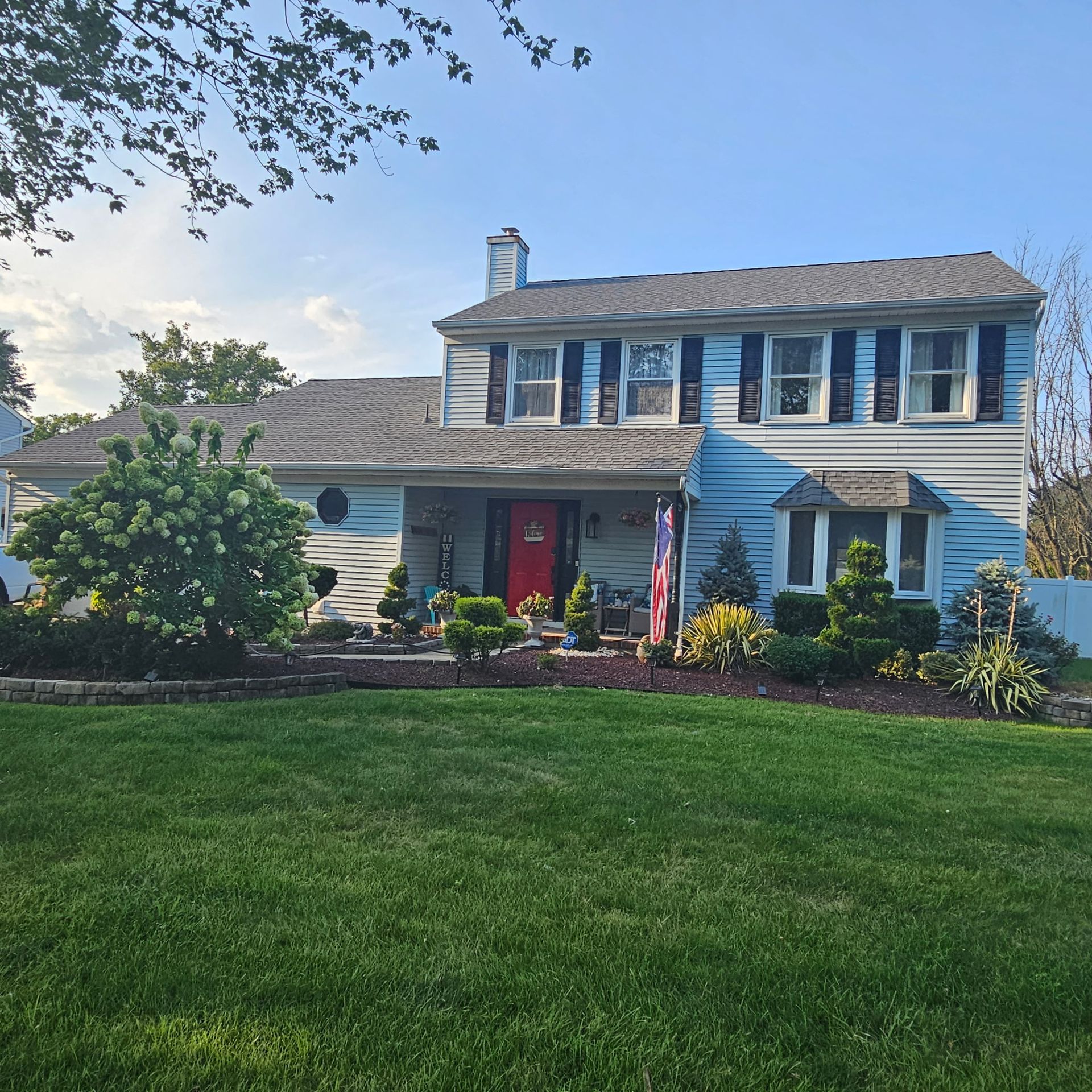 A blue house with a red door and black shutters