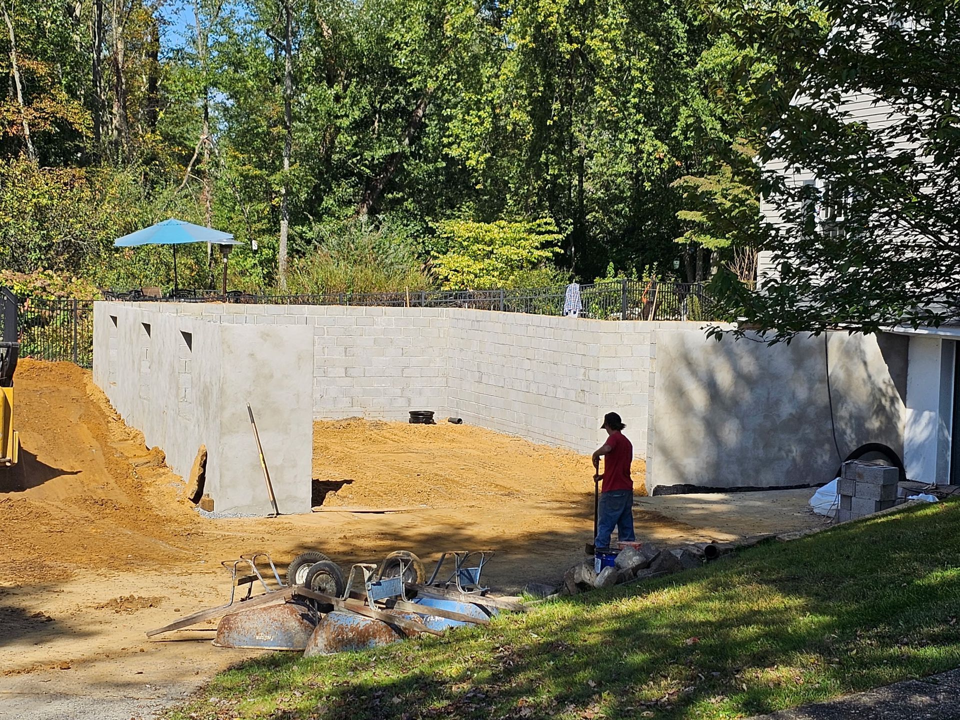 A man is standing in front of a large concrete wall.