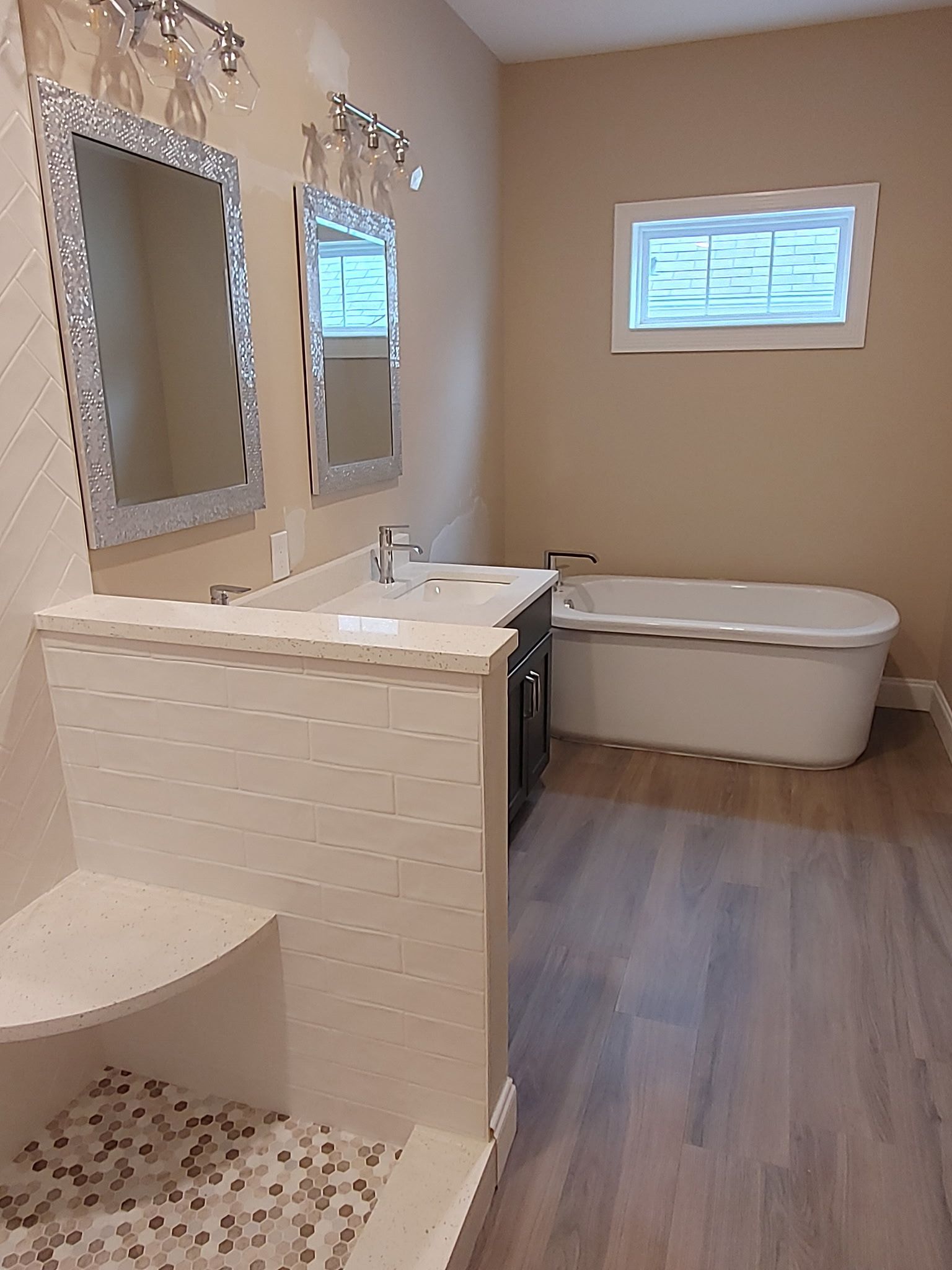A bathroom with a tub , sink , mirrors and a window.