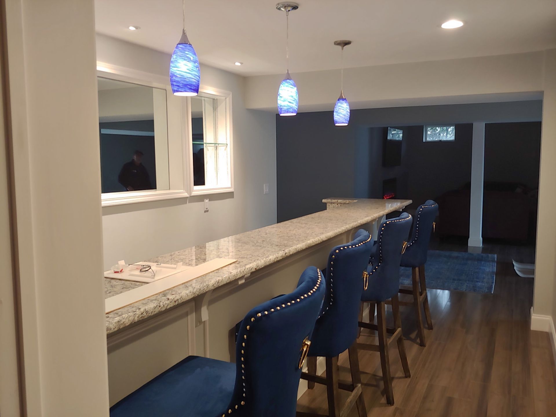 A kitchen with a long counter and blue chairs