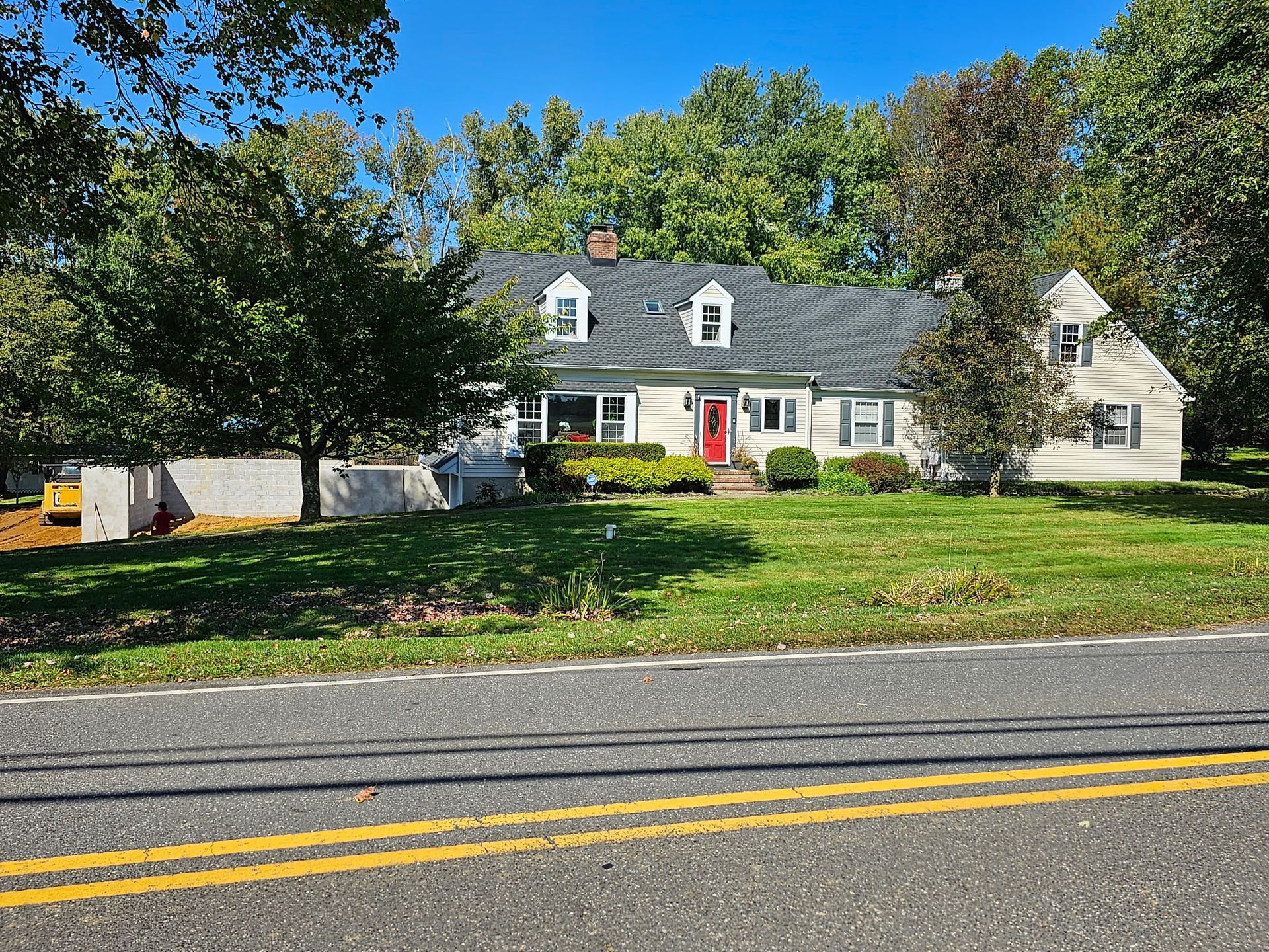 A large white house with a red door is sitting on the side of a road.