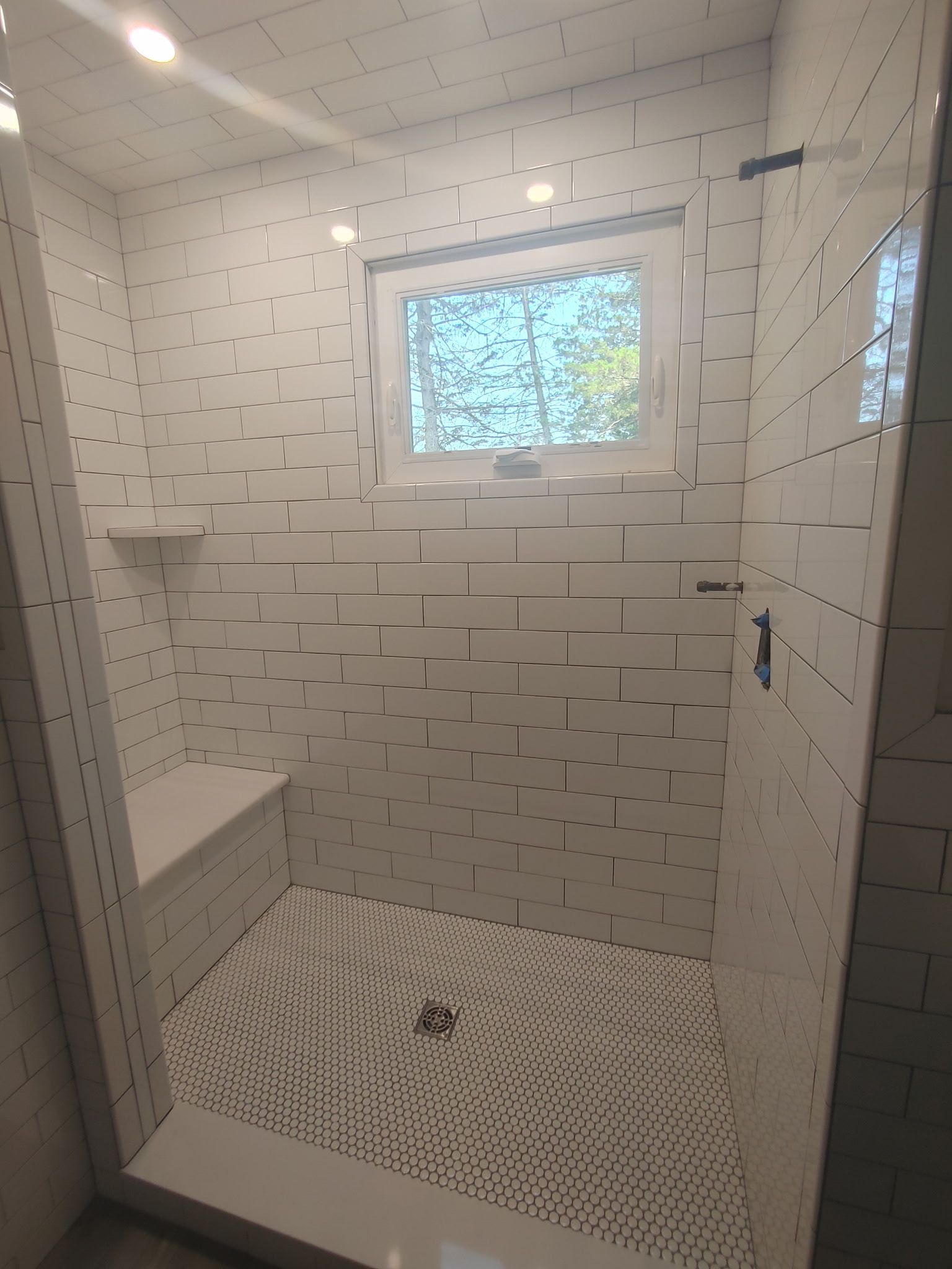 A bathroom with a walk in shower and a window.