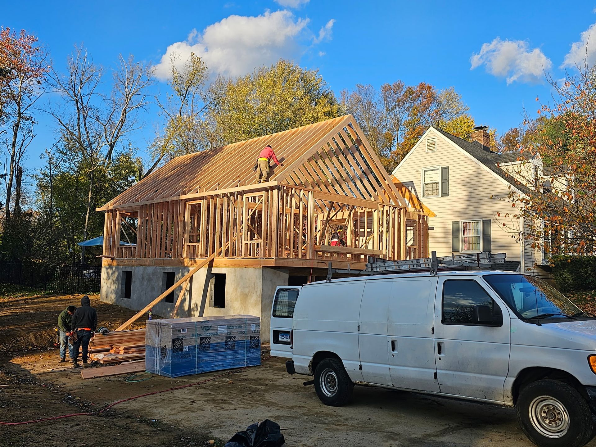 A white van is parked in front of a house under construction