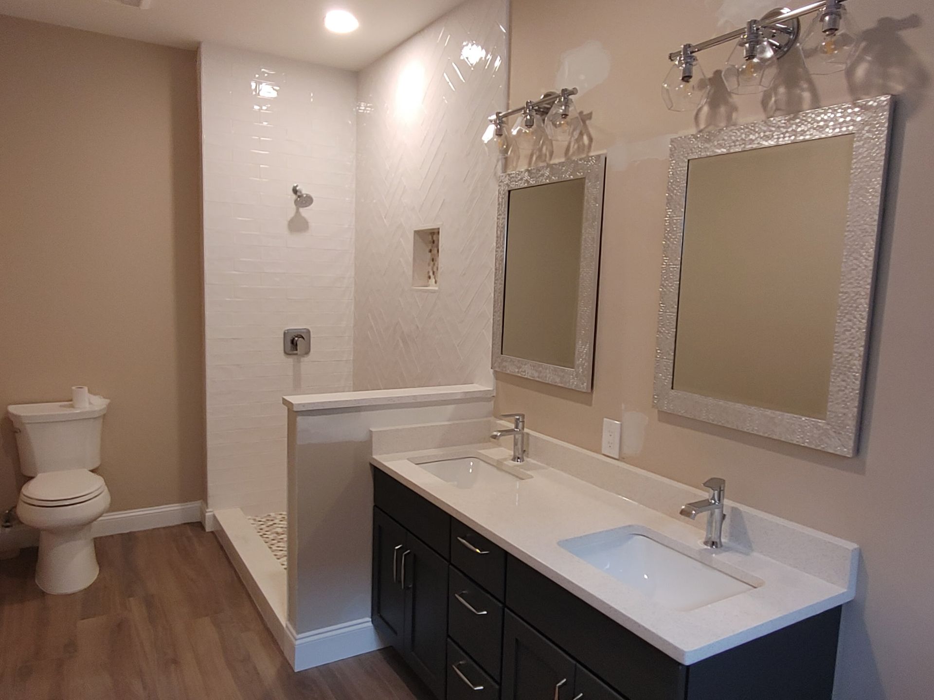 A bathroom with two sinks , a toilet , and two mirrors.