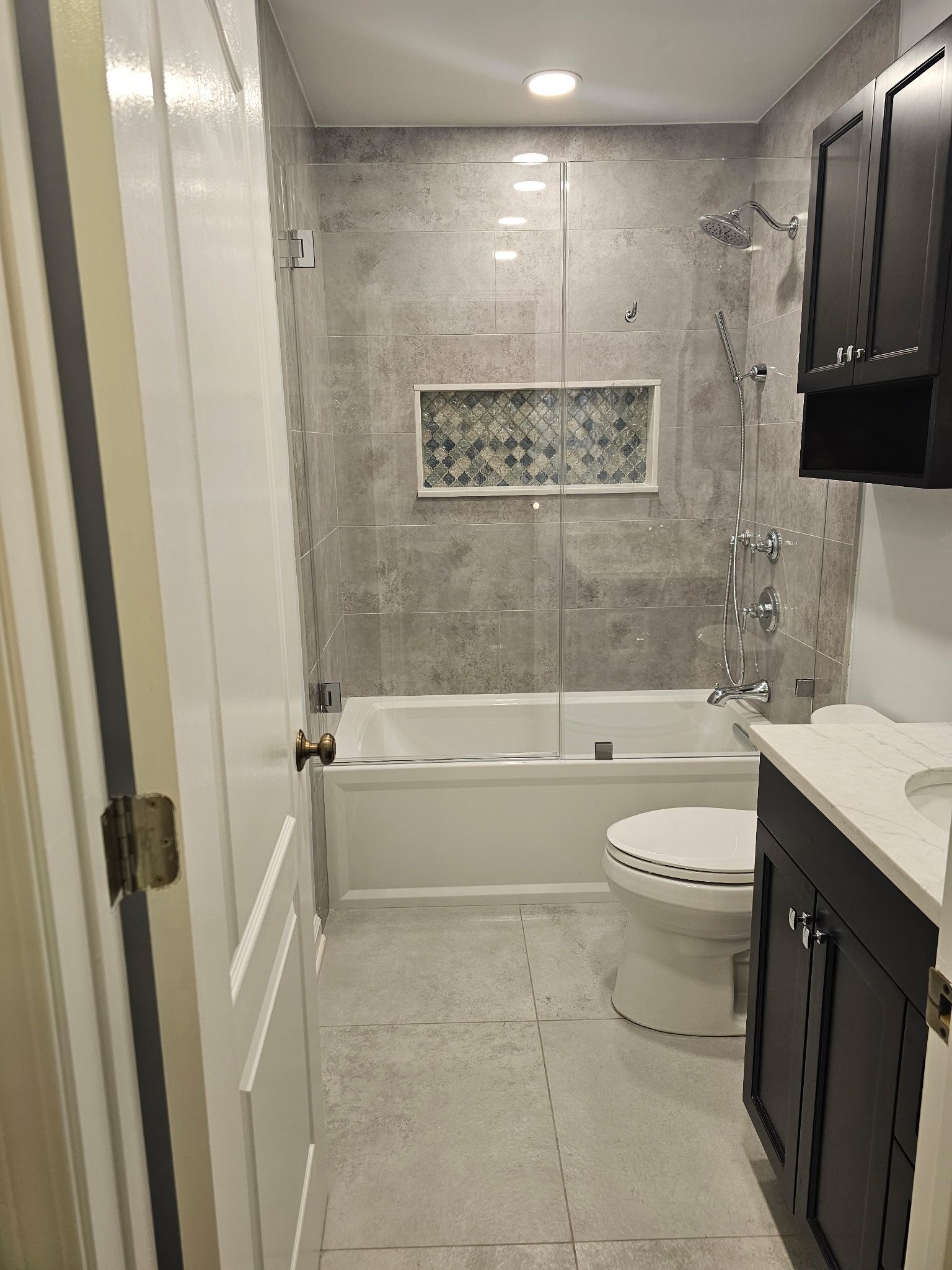A bathroom with a tub , toilet , sink and cabinets.