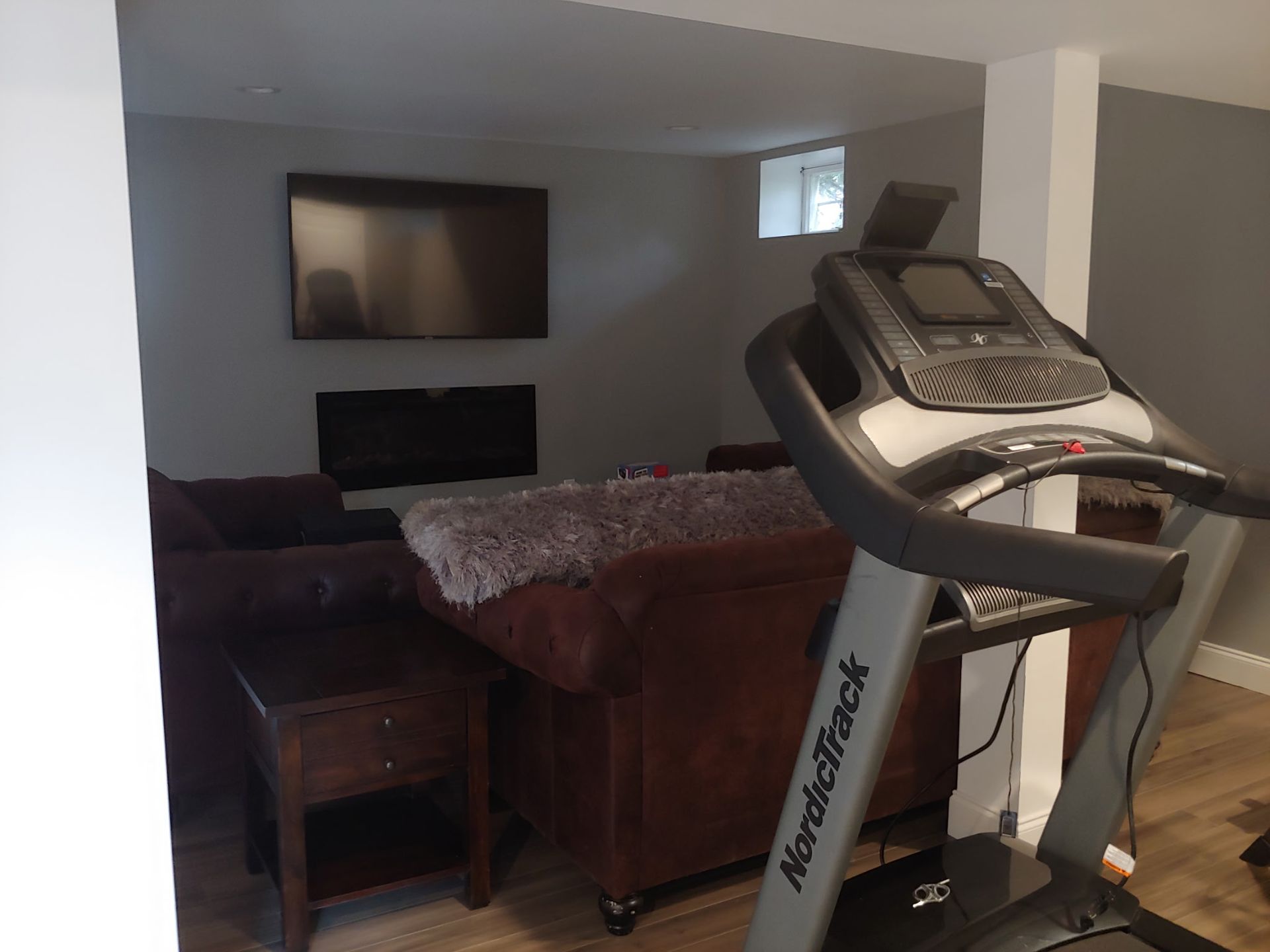A treadmill is sitting in a living room next to a couch.