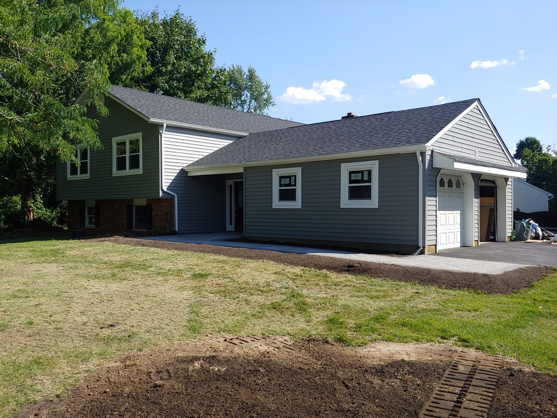 A large house with a lot of windows is sitting on top of a lush green field.