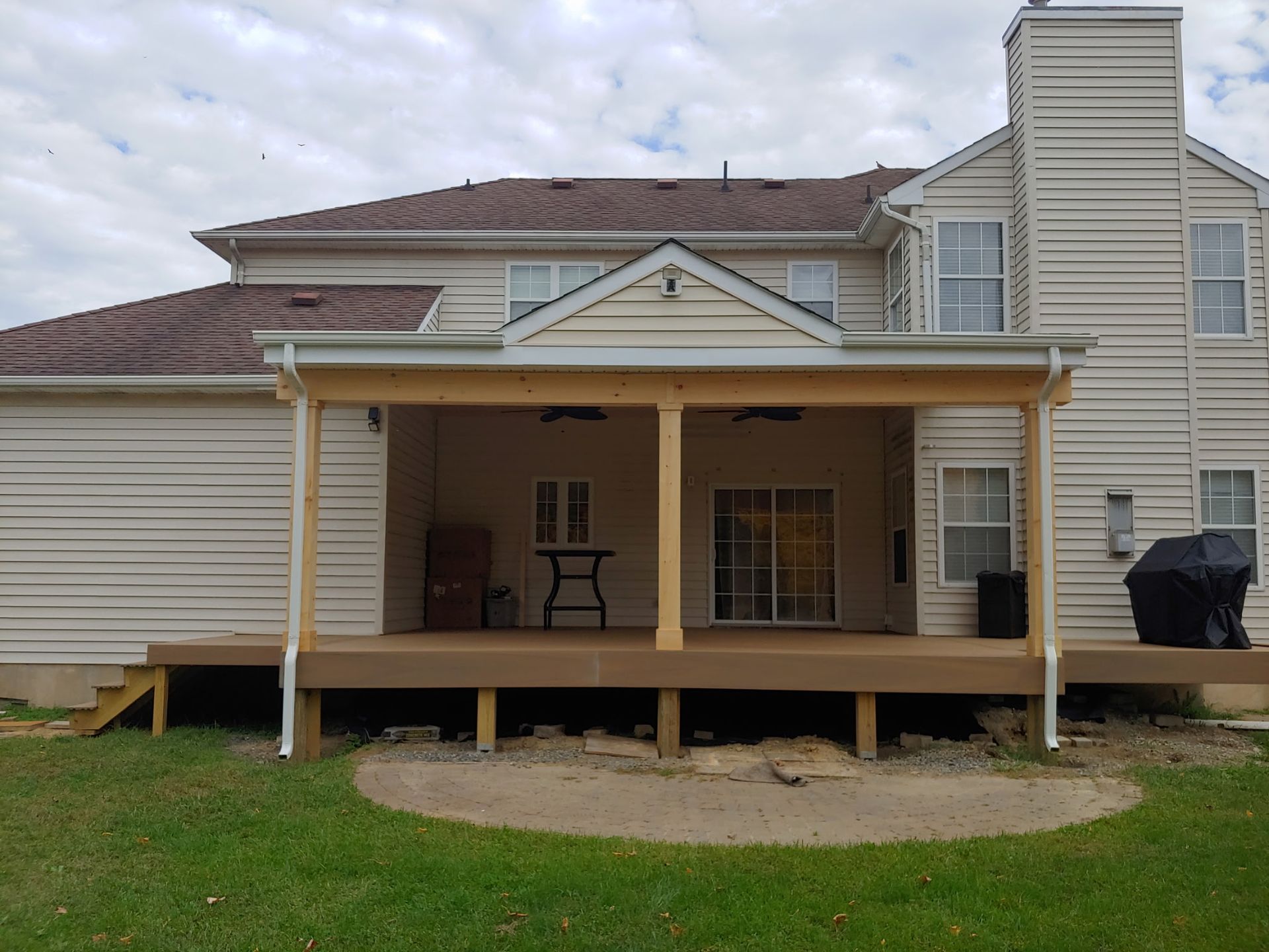 The back of a house with a large porch and a grill.