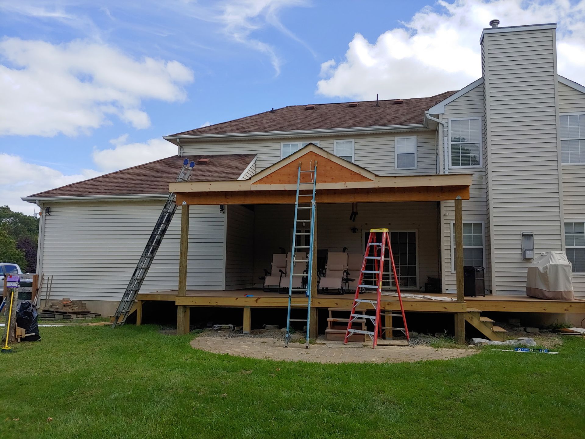 A large white house with a wooden deck under construction.