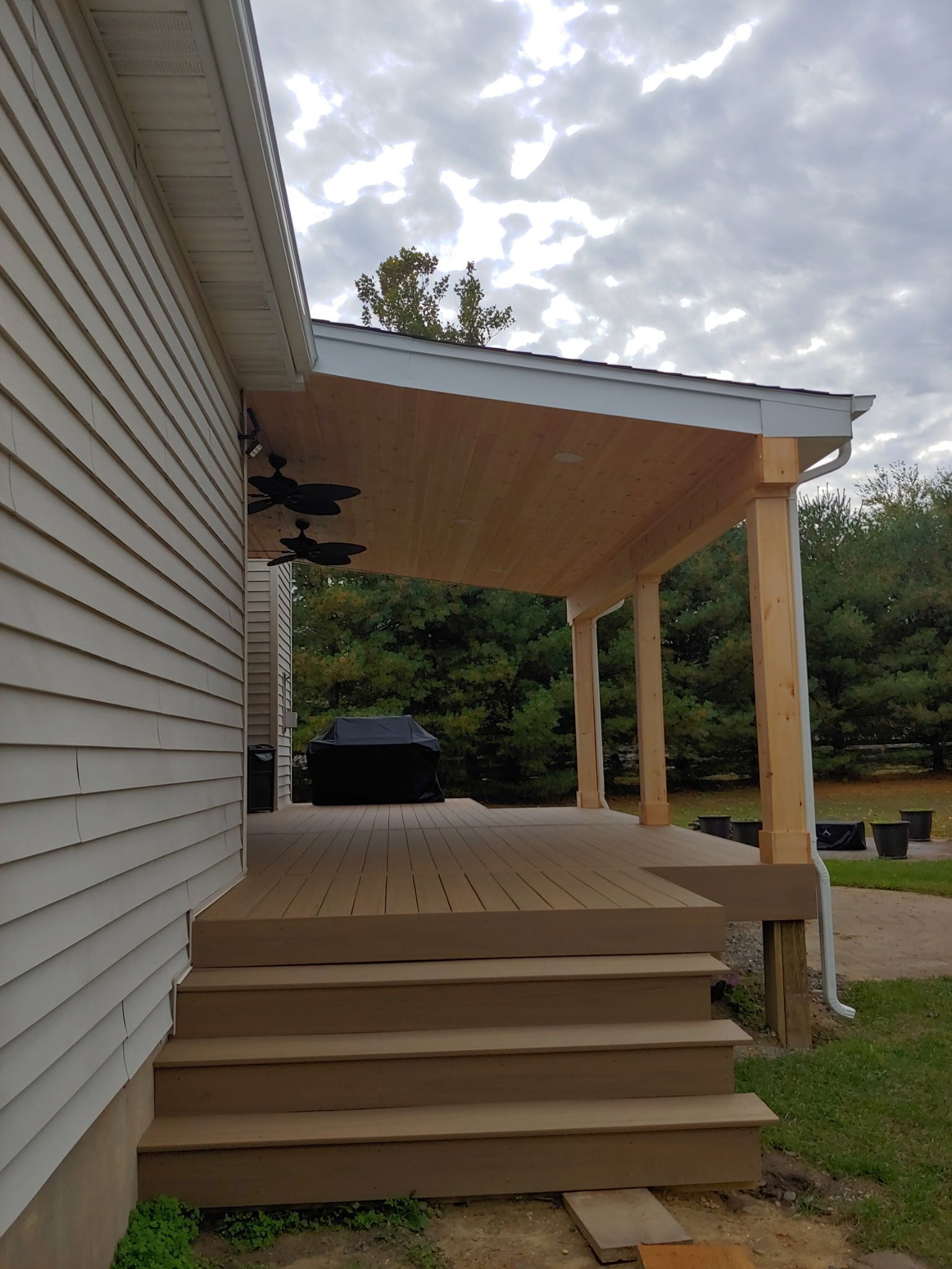 There is a porch with stairs leading up to it next to a house.