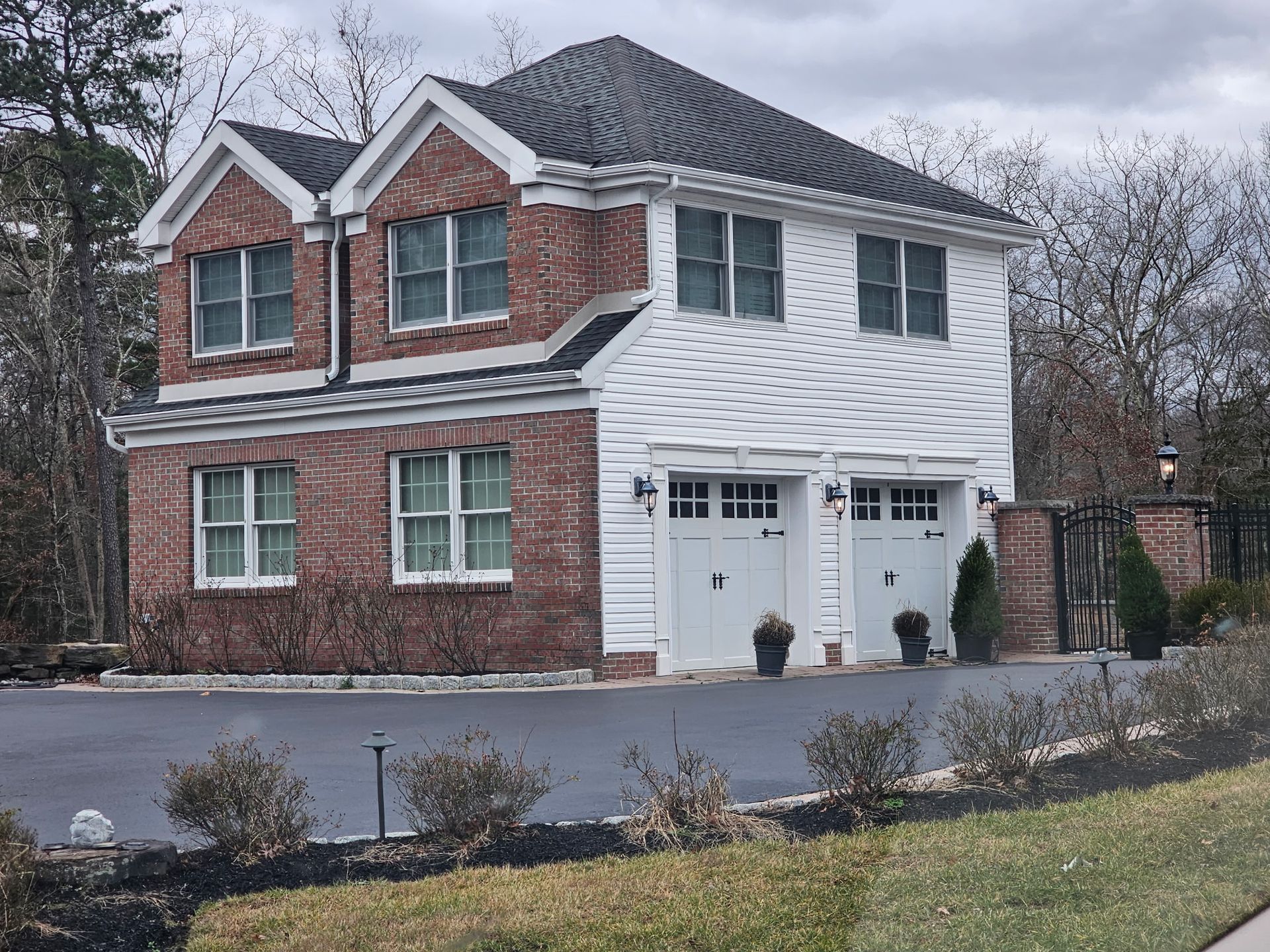A large brick house with a white garage and a driveway.