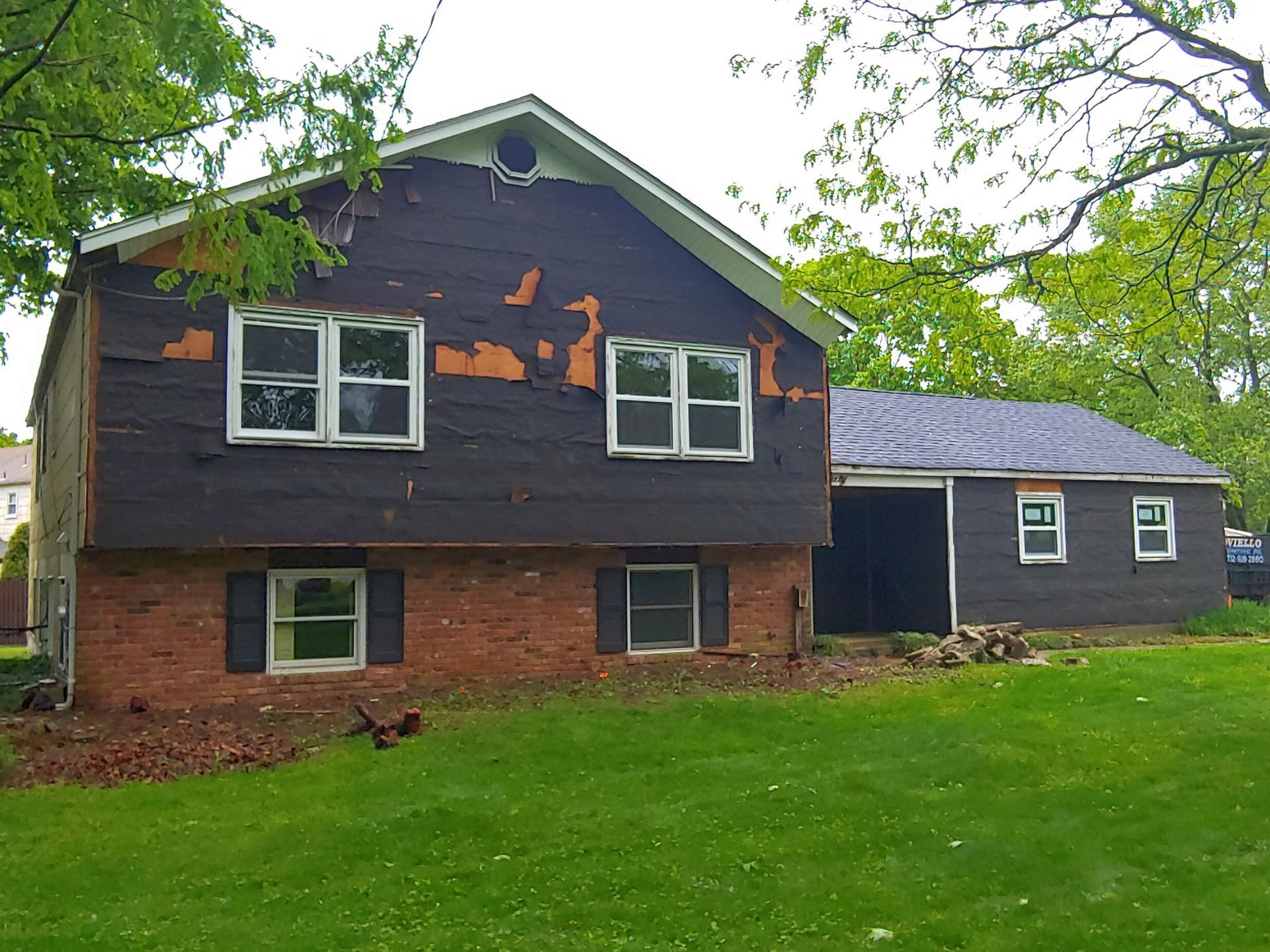 A house with a lot of windows is sitting in the middle of a lush green field.