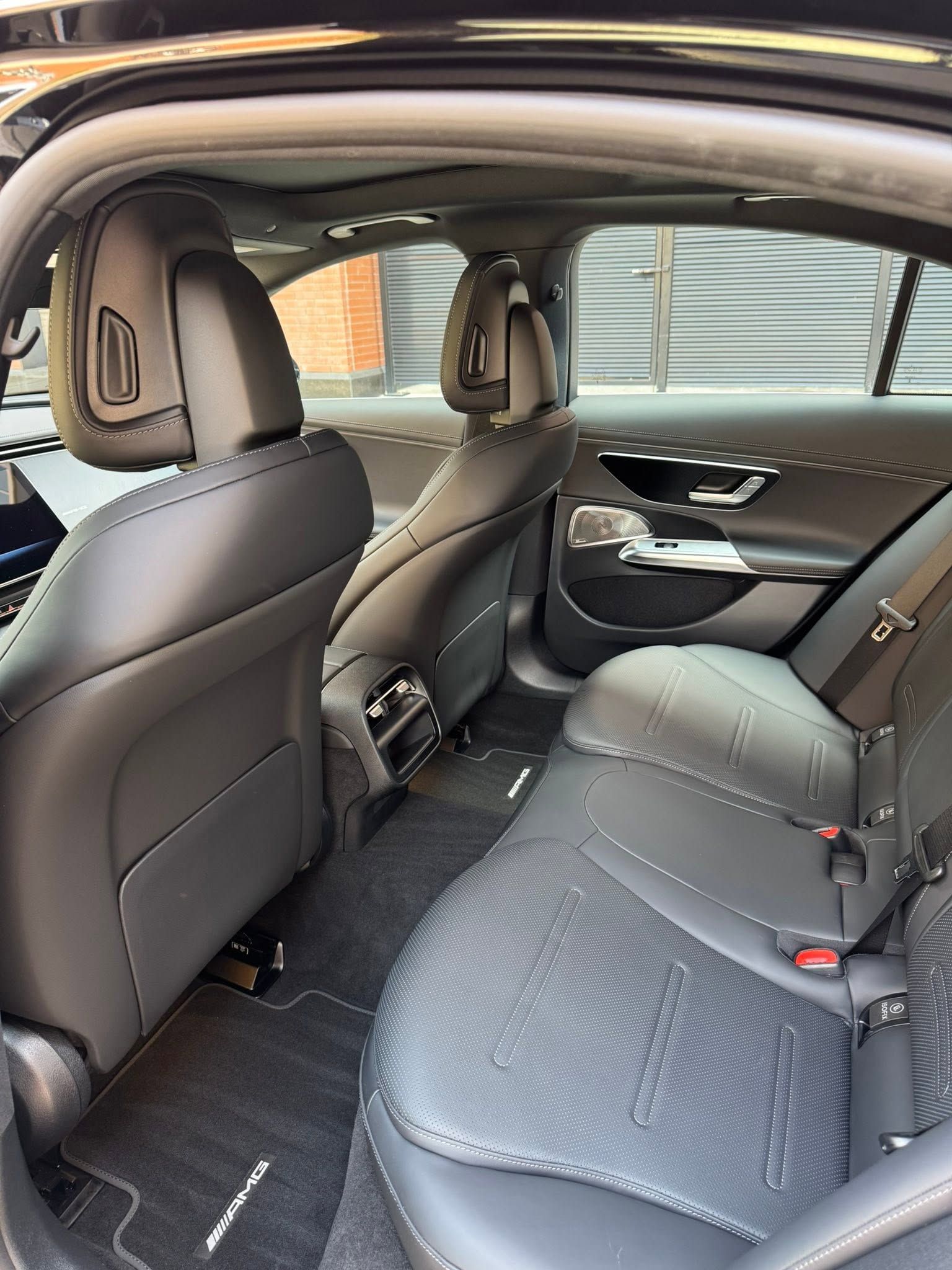 Interior of a black sedan, showing the back seat, front seats, and open rear door.