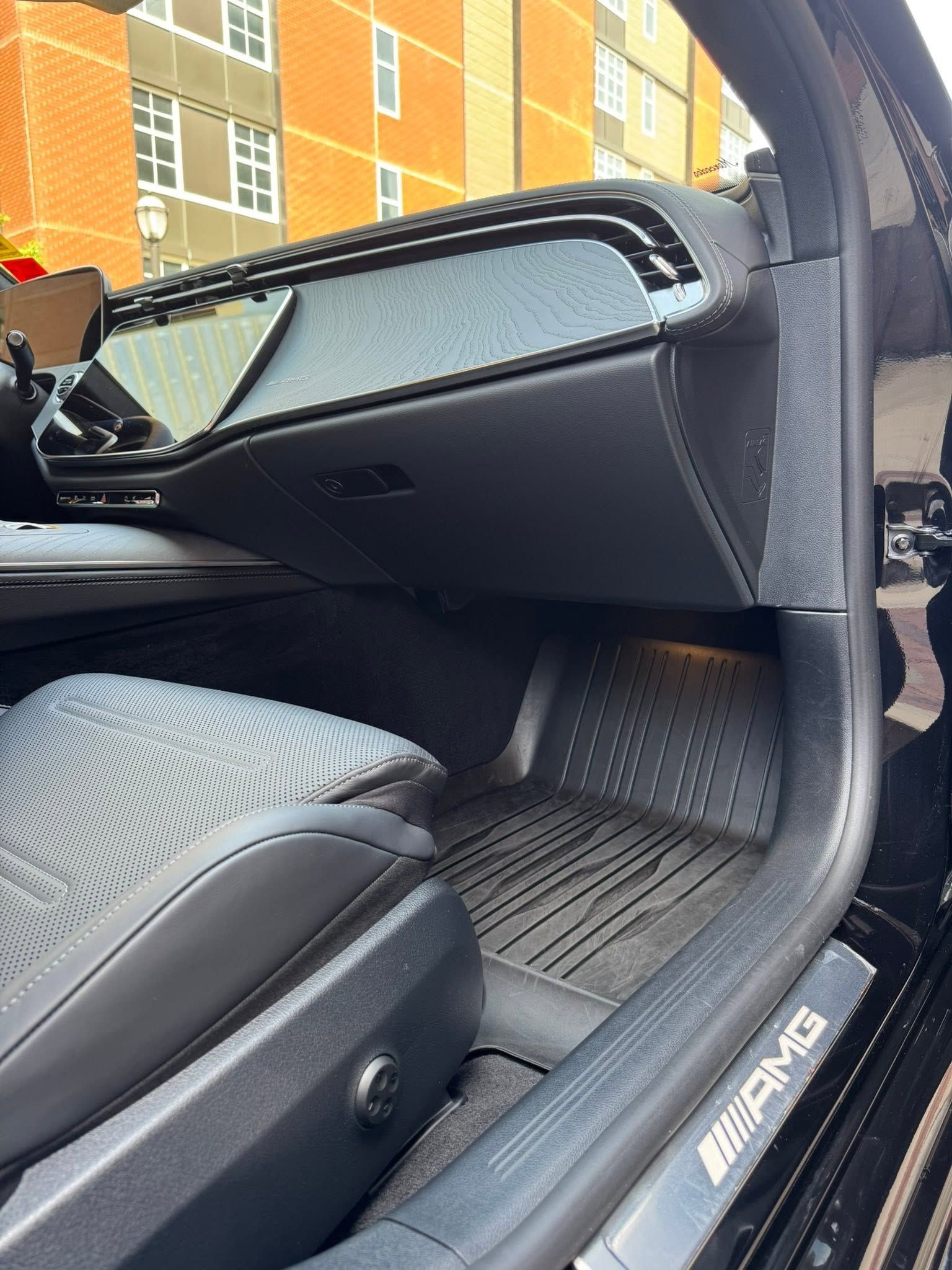 Open car door revealing black leather seat and floor mat inside a Mercedes-Benz interior