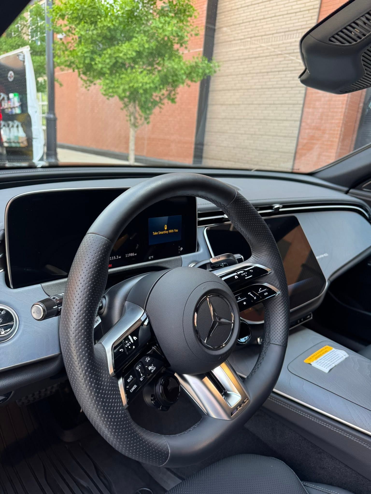 Mercedes-Benz interior with black steering wheel and dashboard, parked outside a building.