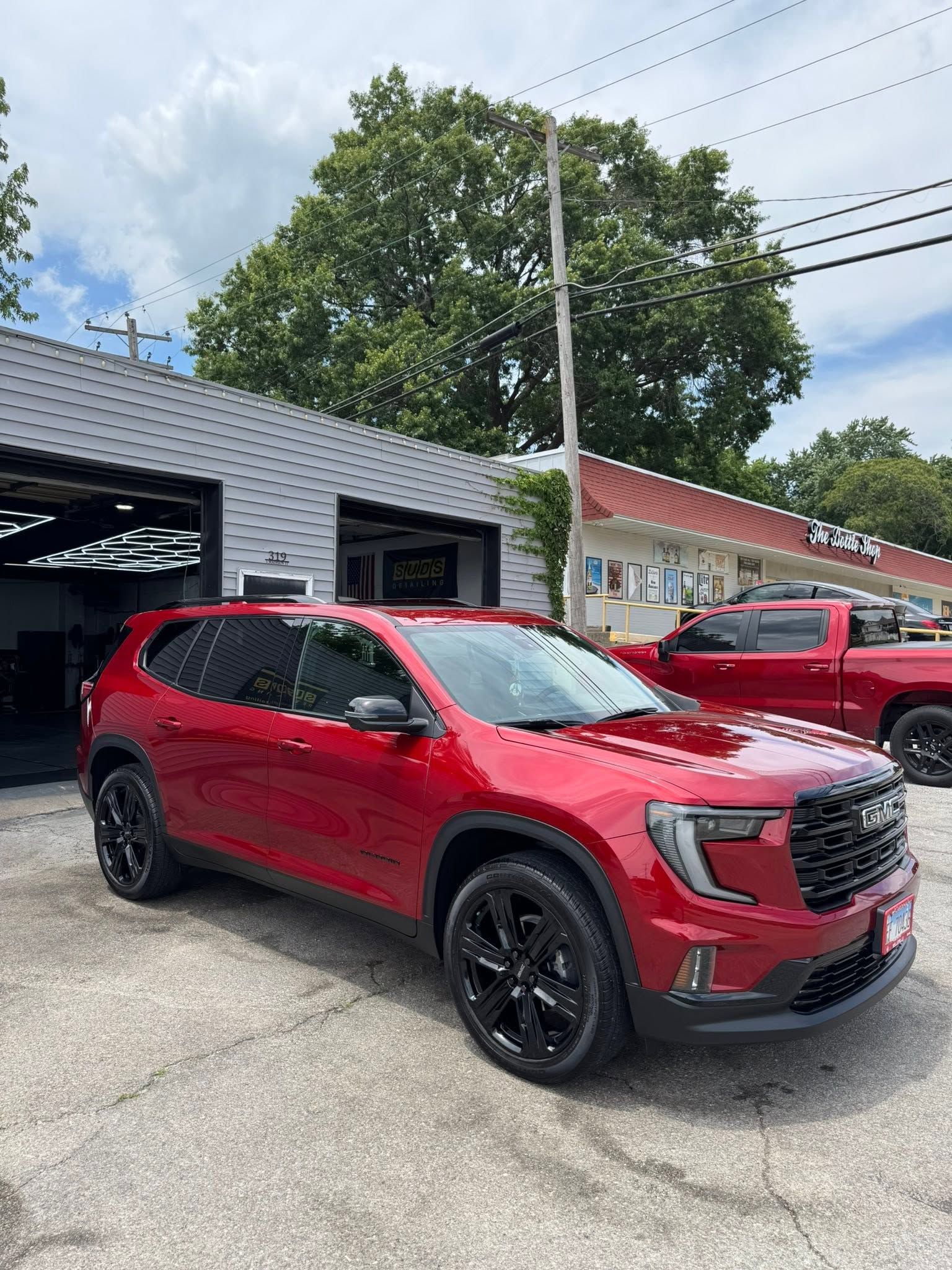 Red SUV parked outside a dealership building with other vehicles nearby.