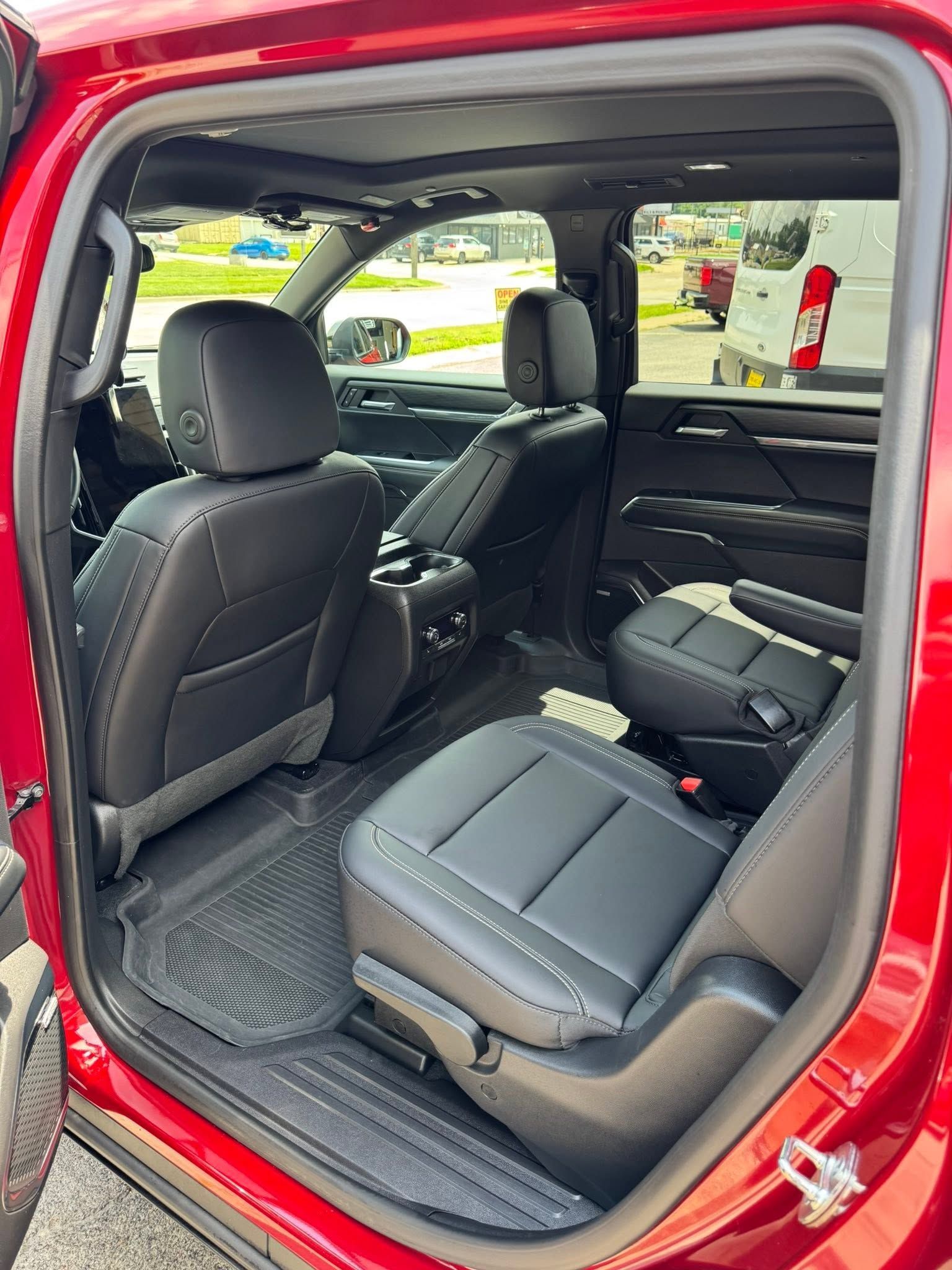 Red SUV interior with folded seats and open rear door, showing a black cargo area and floor mats