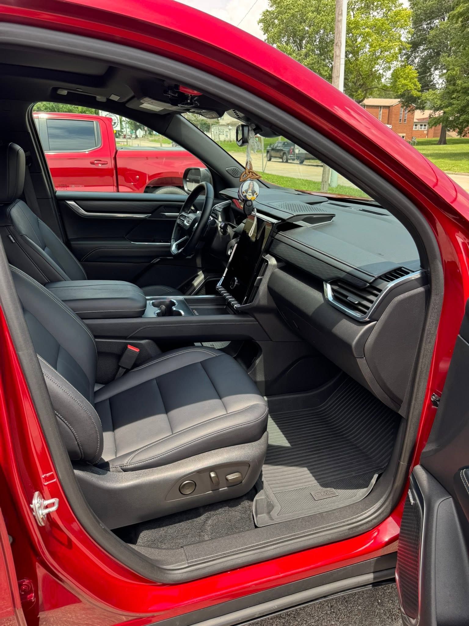 Open red car door showing black leather interior and front seat from the passenger side