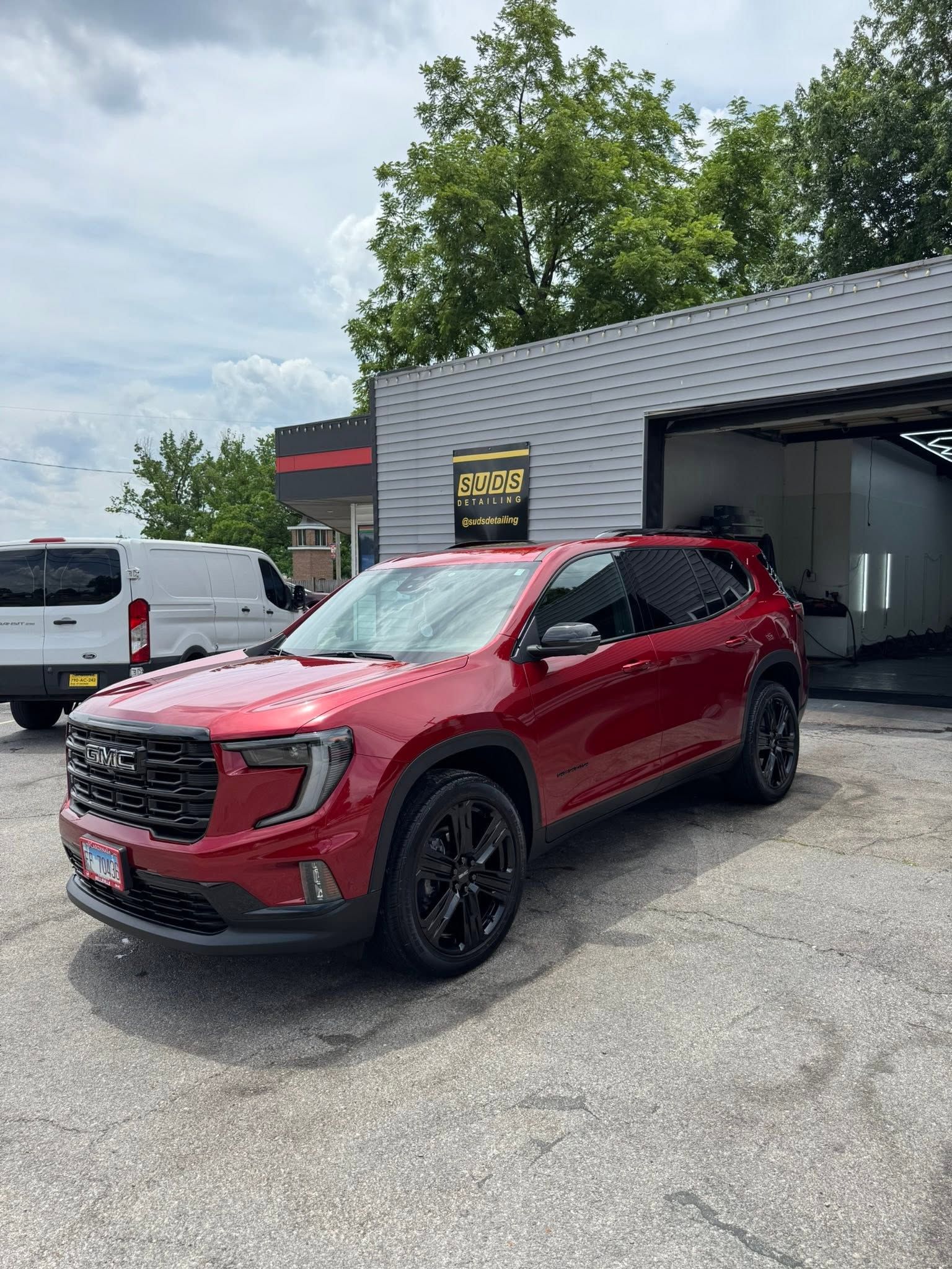 Red SUV parked outside a car wash, with white and gray vehicles nearby.