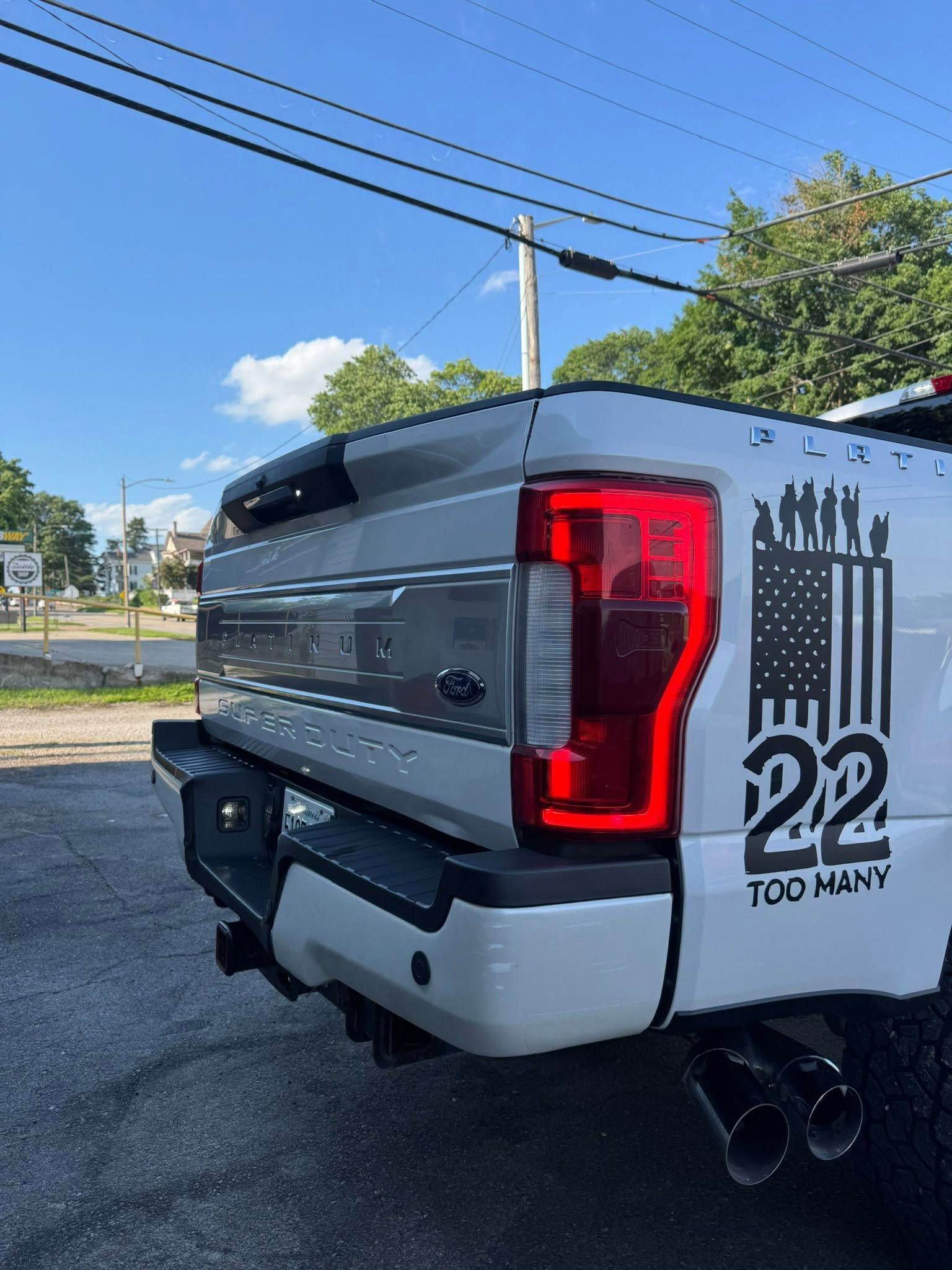 Gray Toyota pickup truck rear with red taillight and custom “22” decal on a sunny street corner