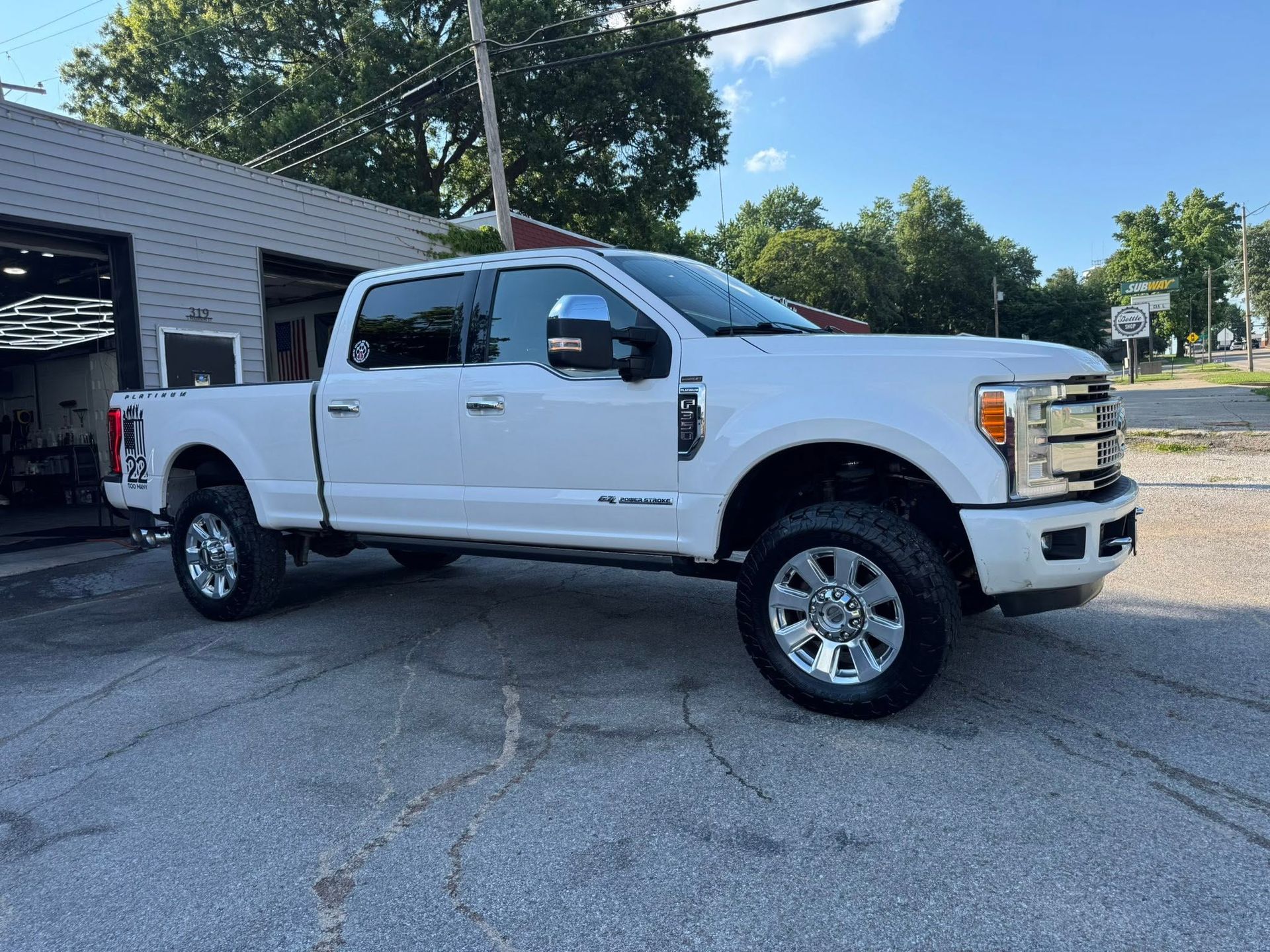 White crew cab pickup truck parked outside a brick building on a sunny day