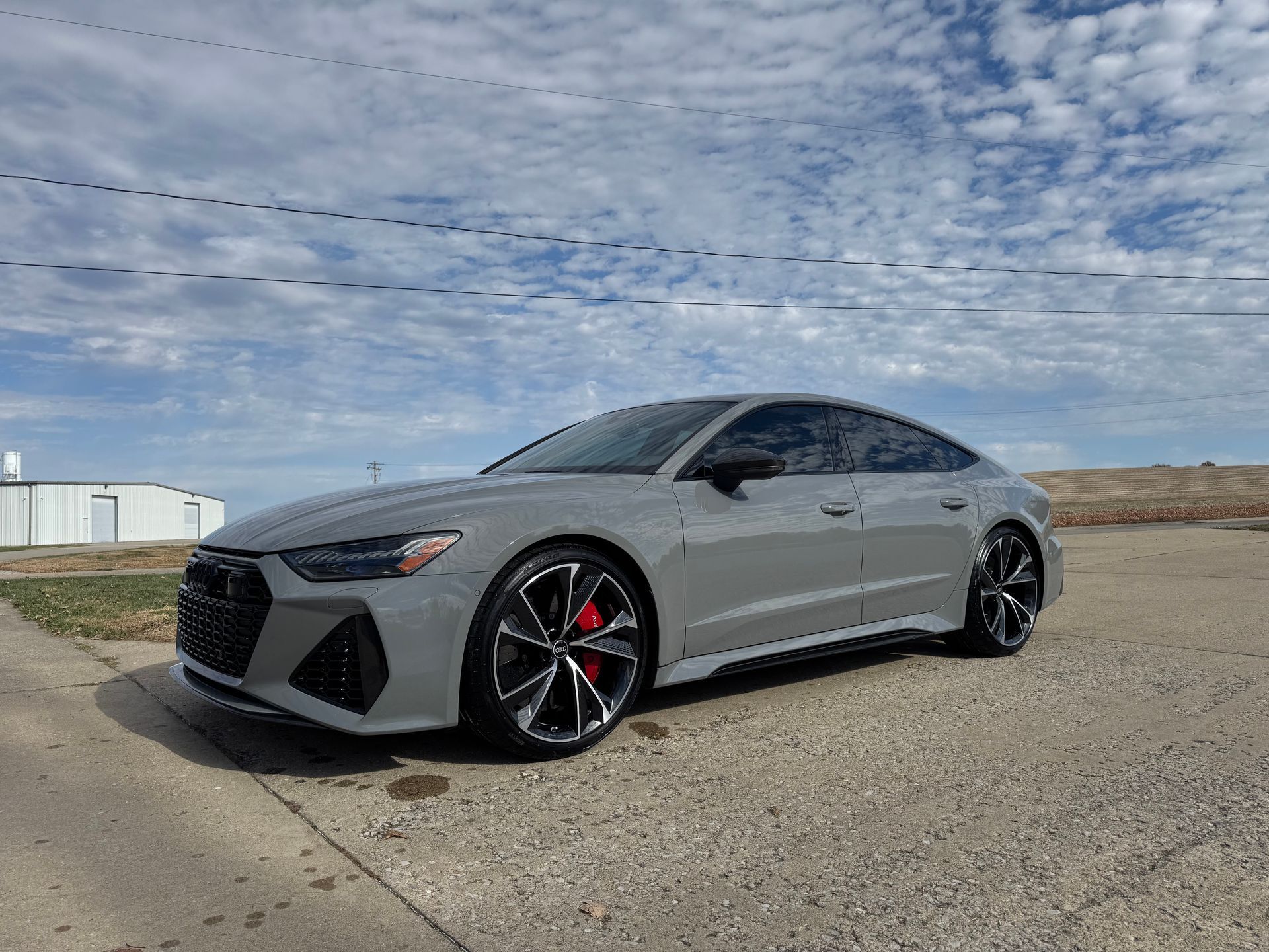 Silver sports sedan parked on a concrete lot under a cloudy sky