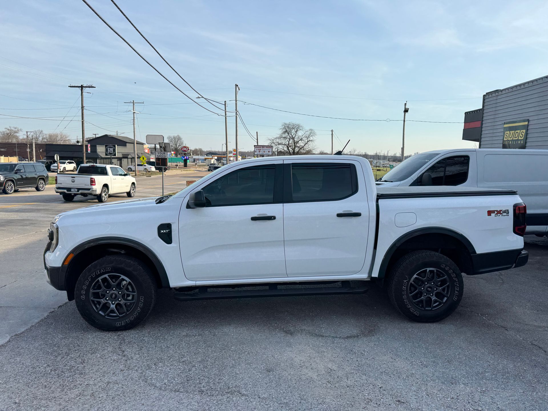 White pickup truck parked in a lot, side view with black wheels and lifted suspension