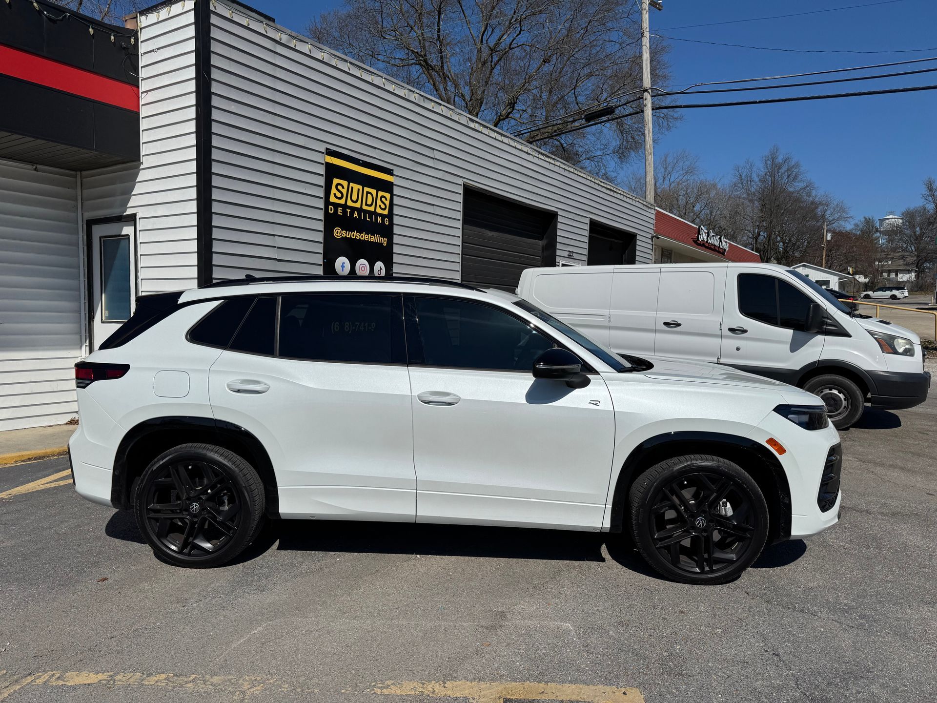 White SUV parked beside a white van outside a building on a sunny day