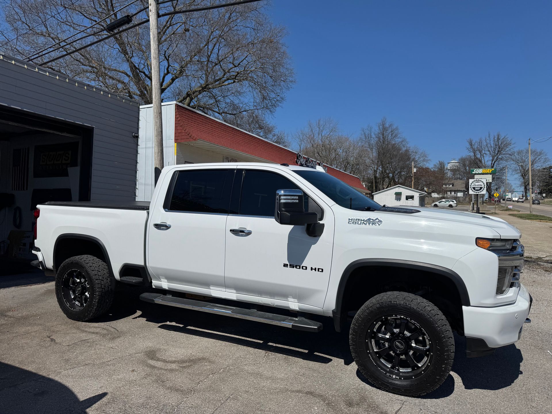 White lifted pickup truck parked outside a building on a sunny day