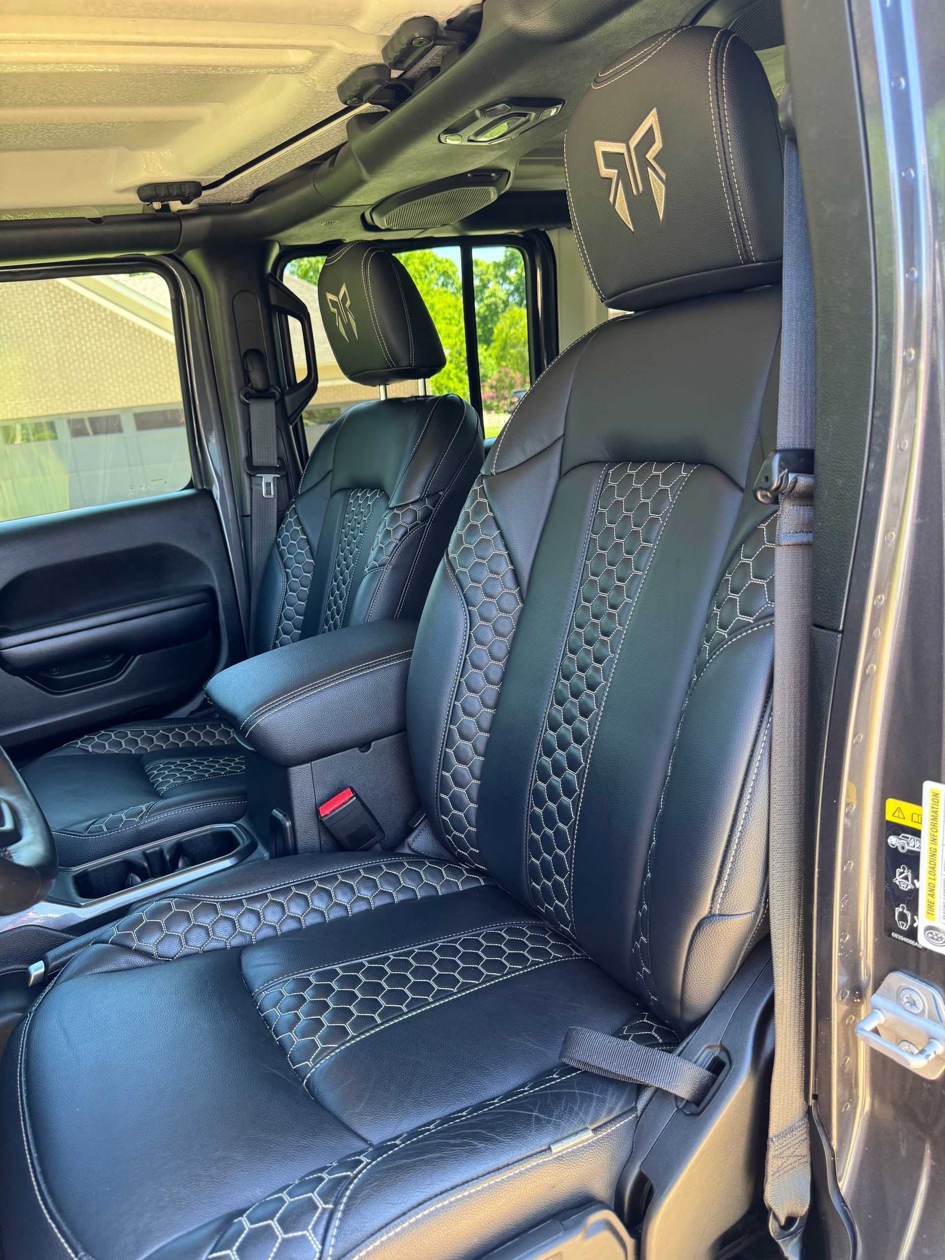 Black leather car seats with diamond stitching and headrest, viewed through an open vehicle door