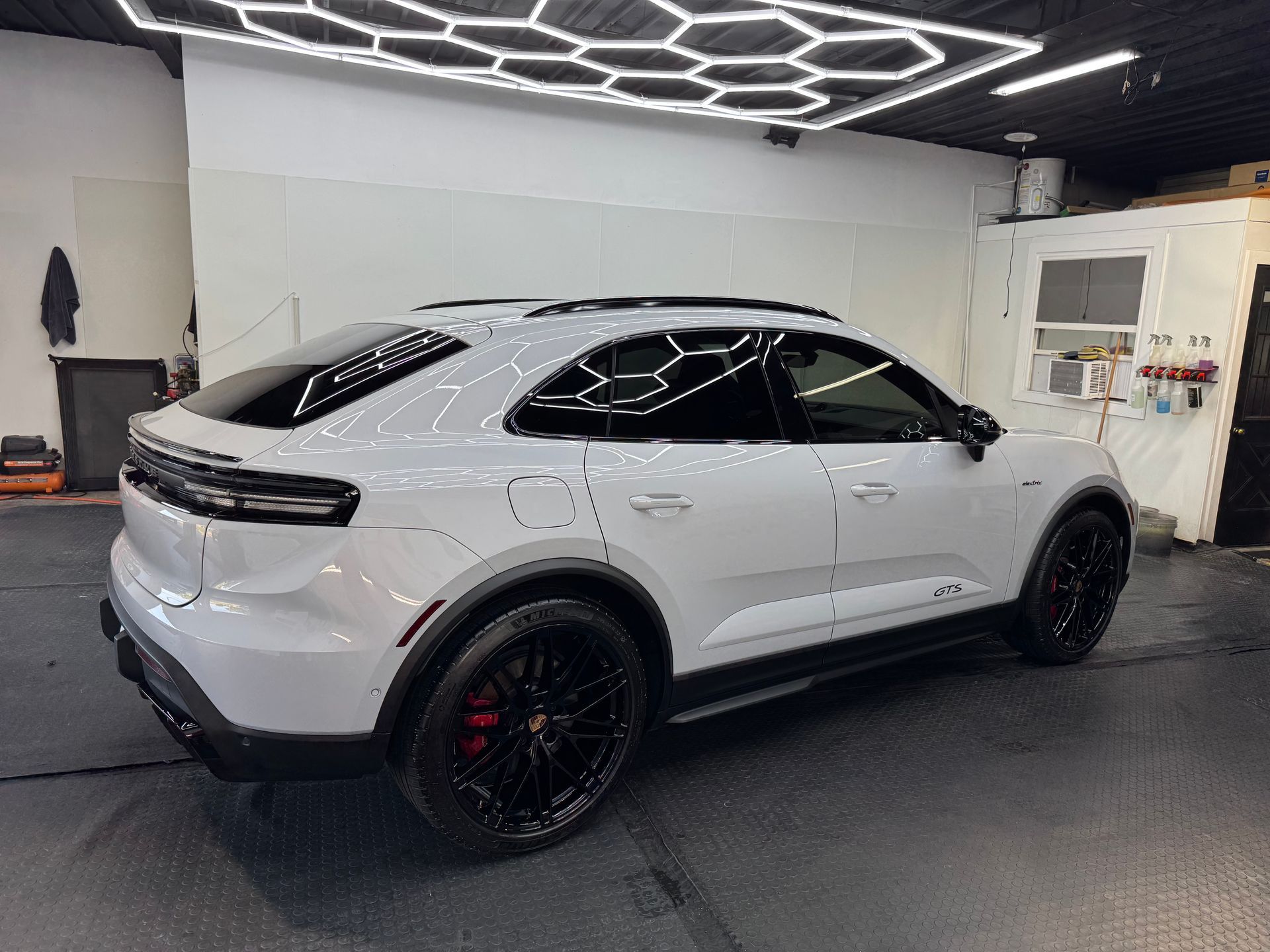 White SUV with black rims parked indoors under geometric ceiling lights