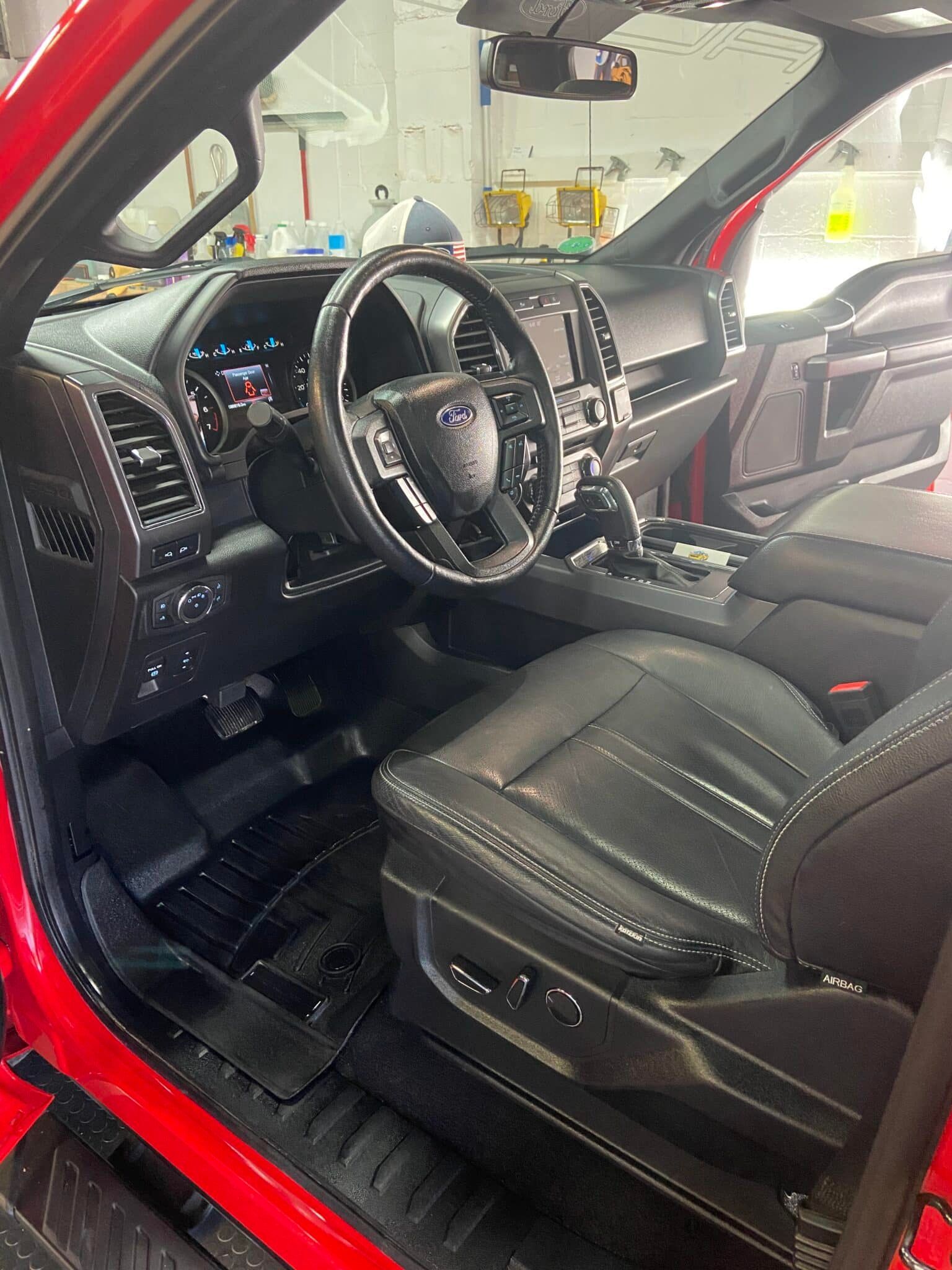 Black pickup truck interior with red exterior, leather seats, steering wheel, and open driver door