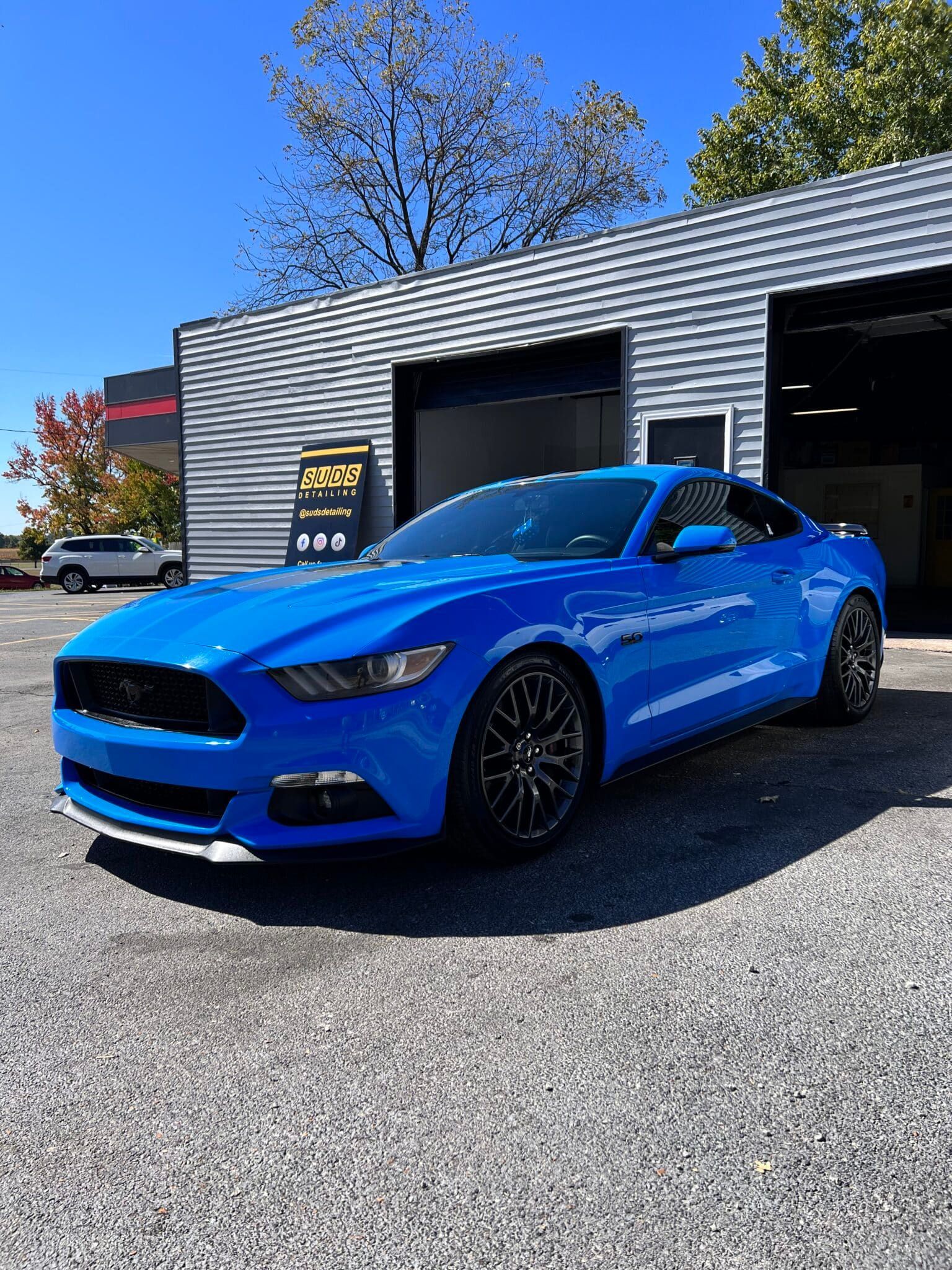 Blue sports car parked outside a garage on a sunny day