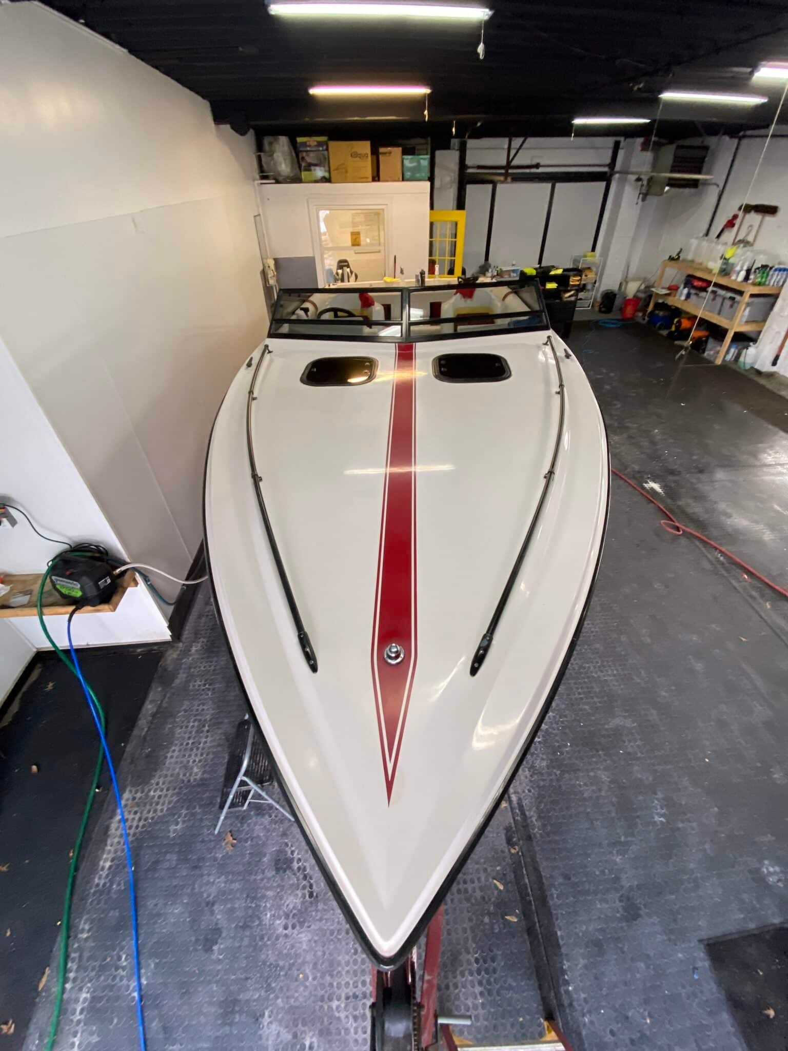 White speedboat with a red stripe in a garage, viewed from the bow.
