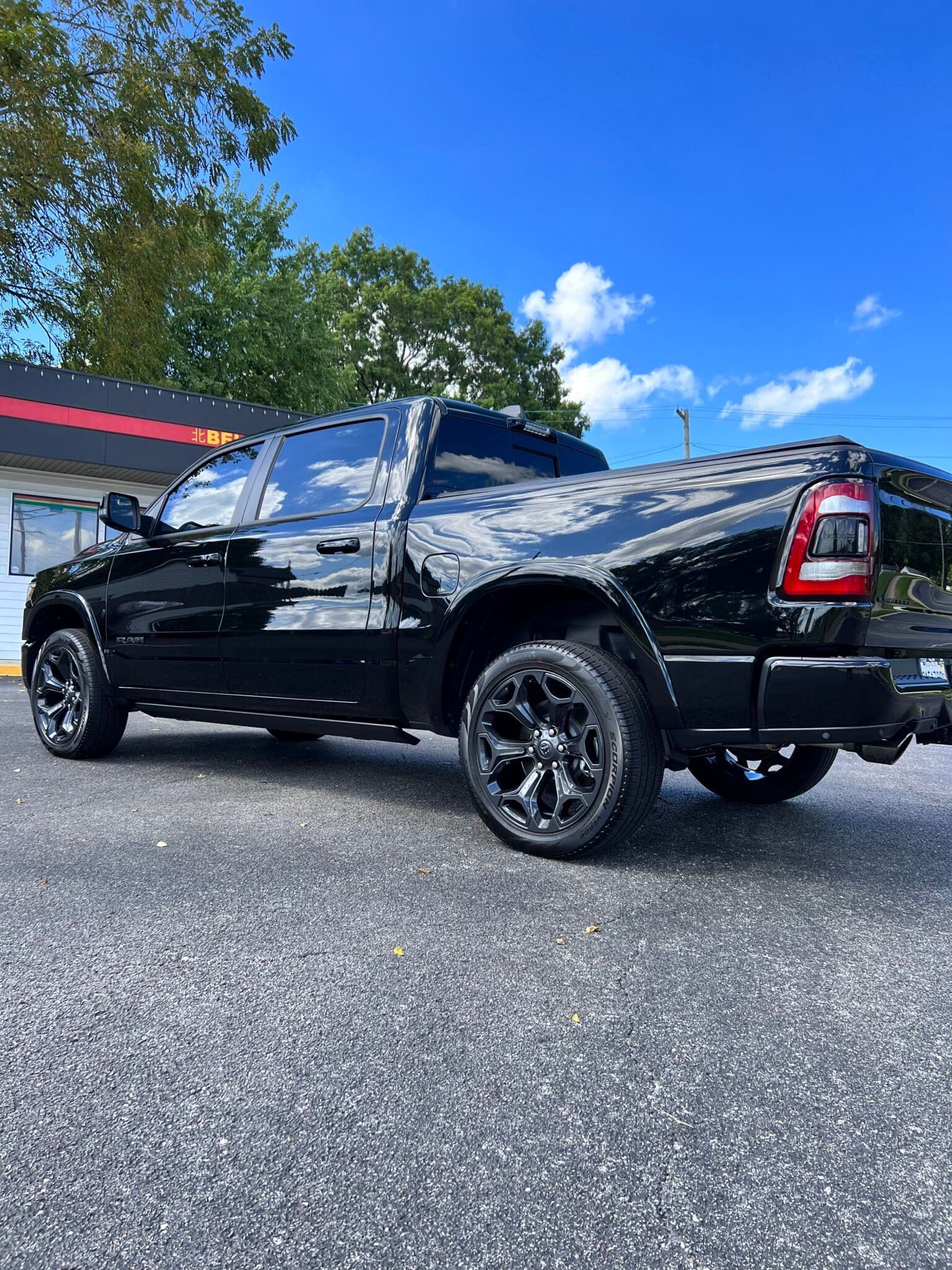 Black pickup truck with custom rims parked outdoors on a sunny day
