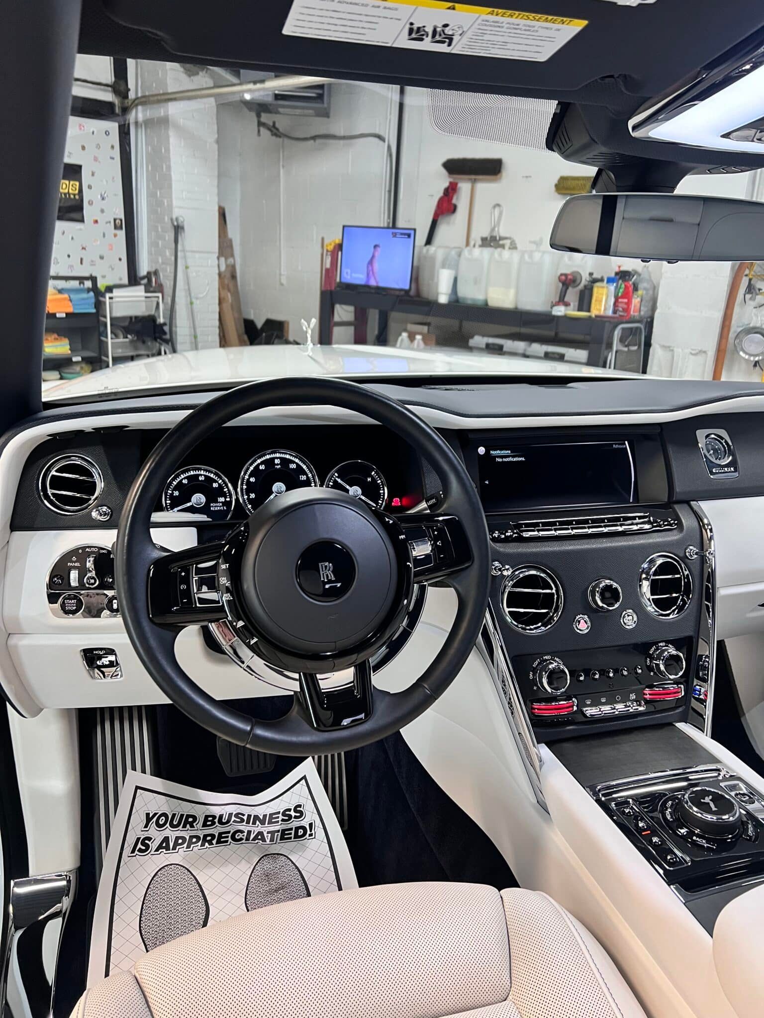 Luxury car interior with black-and-white dashboard, steering wheel, and center console in a garage