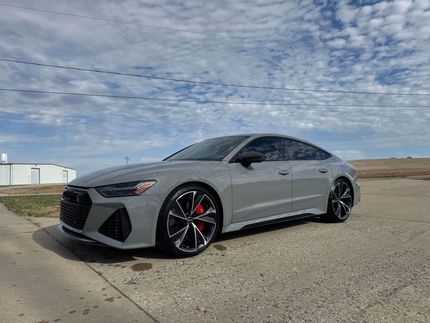 Gray sports sedan parked on a roadside under a cloudy sky, front three-quarter view