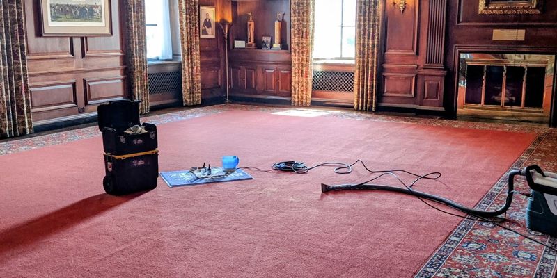 A room with a red carpet and a vacuum cleaner on the floor.