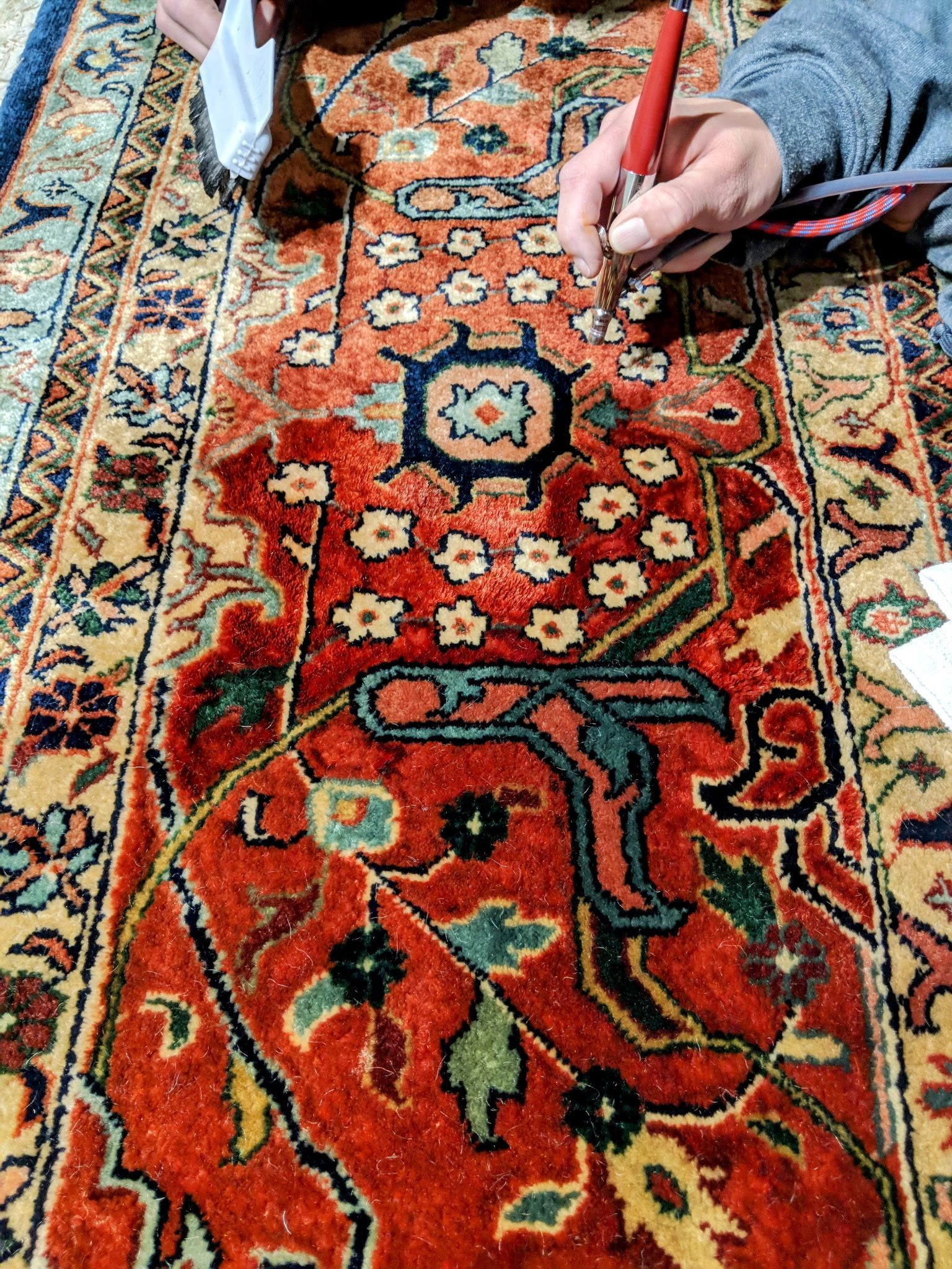 A person is writing on a rug with a pen.