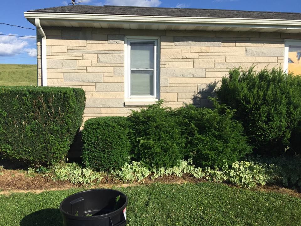 A brick house with a black trash can in front of it