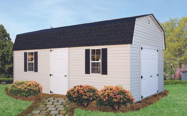 Tan and white barn-style shed with black roof and shutters, sitting on green grass with a stone path.