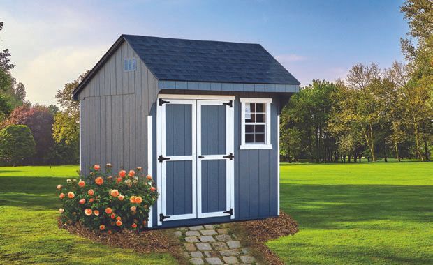 Blue shed with white trim, double doors, window, and pathway, in a grassy yard.