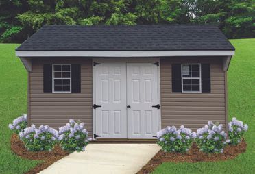 Tan shed with black roof, white doors, black shutters, and lavender bushes in front.