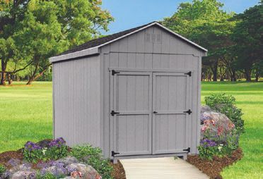 Gray wooden shed with double doors in a grassy yard, pathway leading to it.